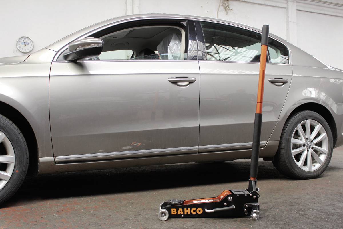 Ein silbernes Auto steht in einer Garage, direkt davor ein Hebelwagenheber der Marke Bahco auf dem Boden.