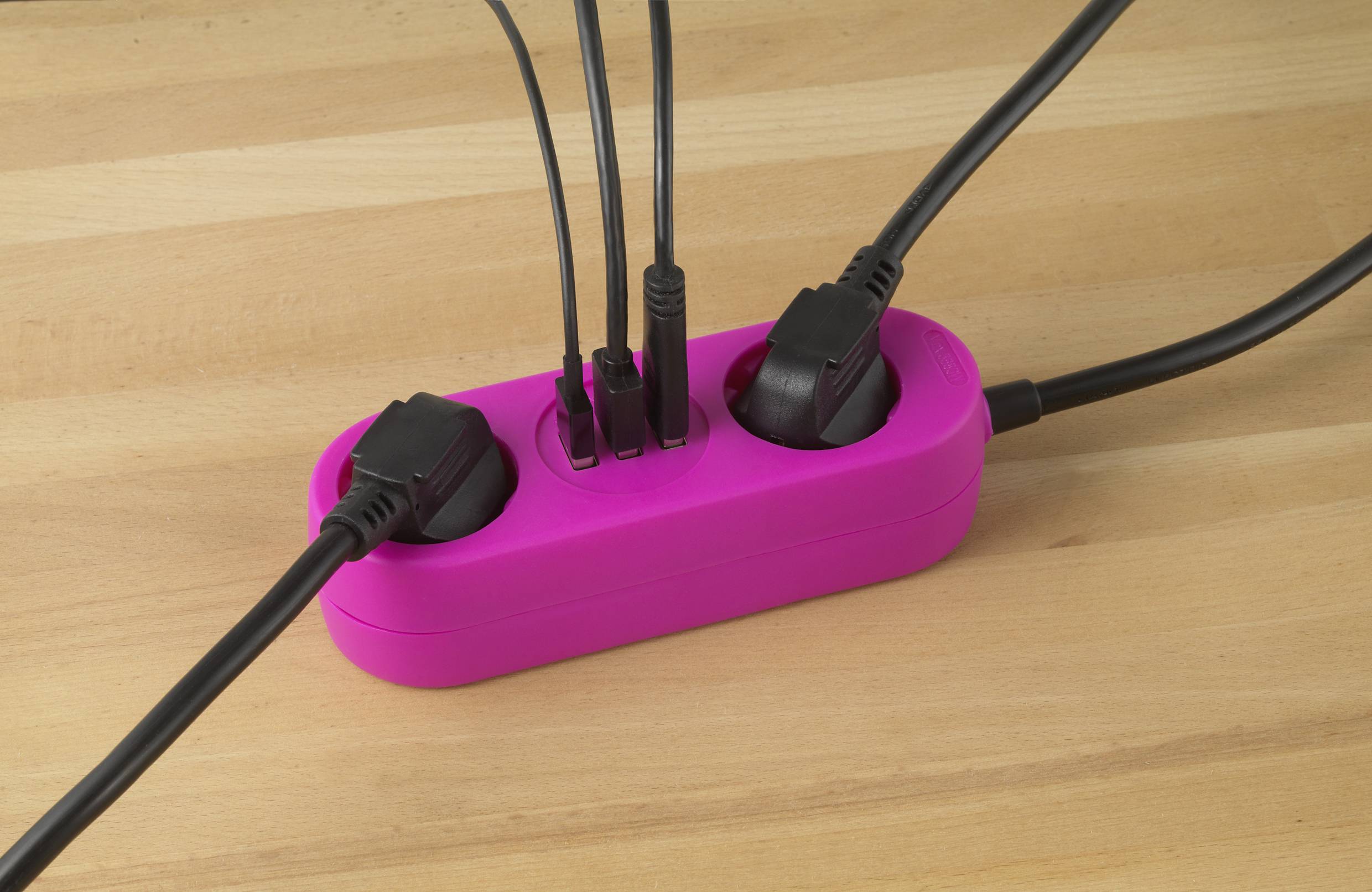 Eine pinke Mehrfachsteckdose auf Holztisch, mit mehreren eingesteckten schwarzen Kabeln, wodurch Stromanschlüsse effizient genutzt werden.