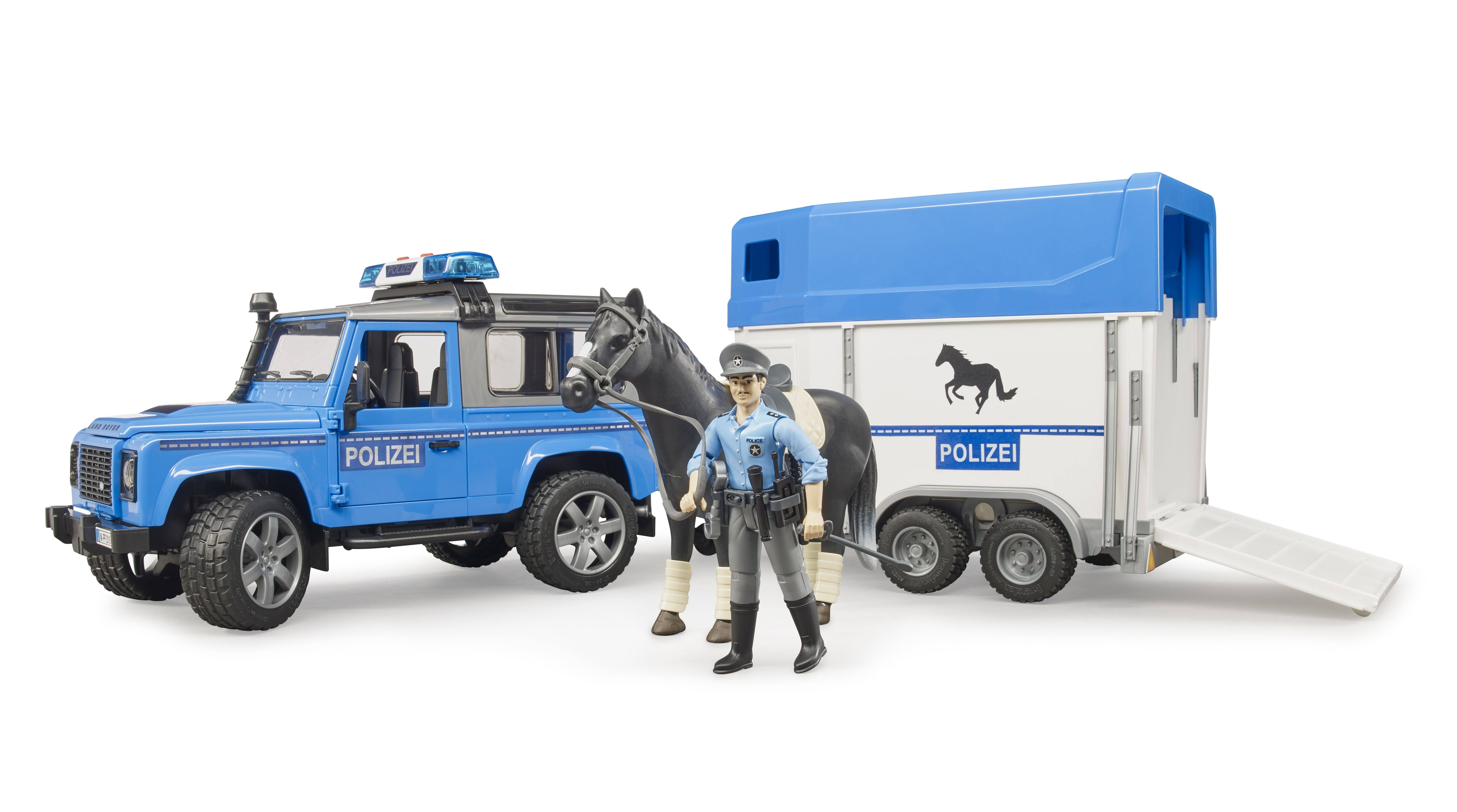 Ein Spielzeugset mit Polizeiauto, Pferd und Pferdeanhänger. Ein Polizist in Uniform steht neben den Fahrzeugen.