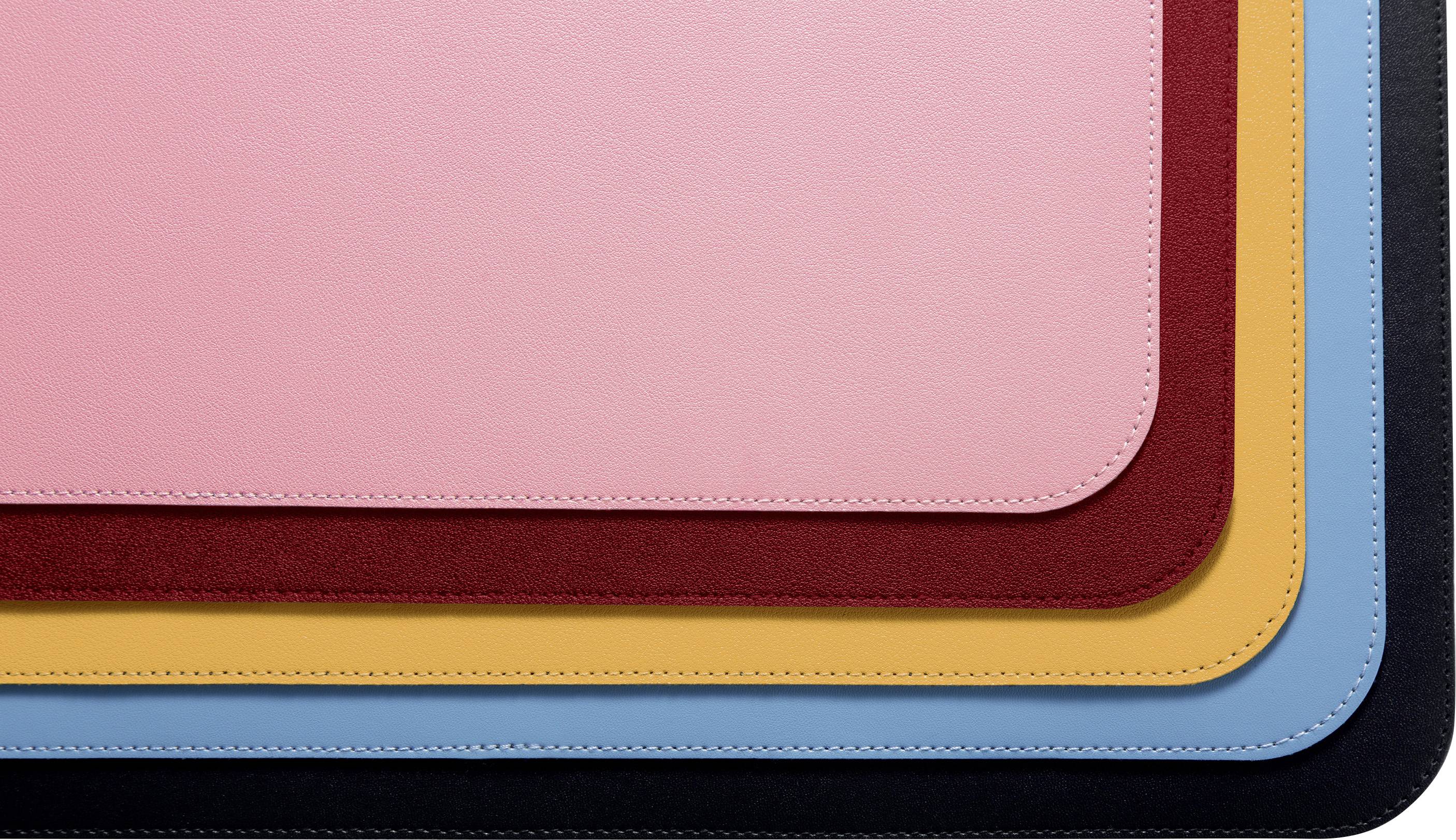 Verschiedene Lagen von farbigen, rechteckigen Lederunterlagen liegen übereinander: rosa, rot, orange, blau und schwarz.