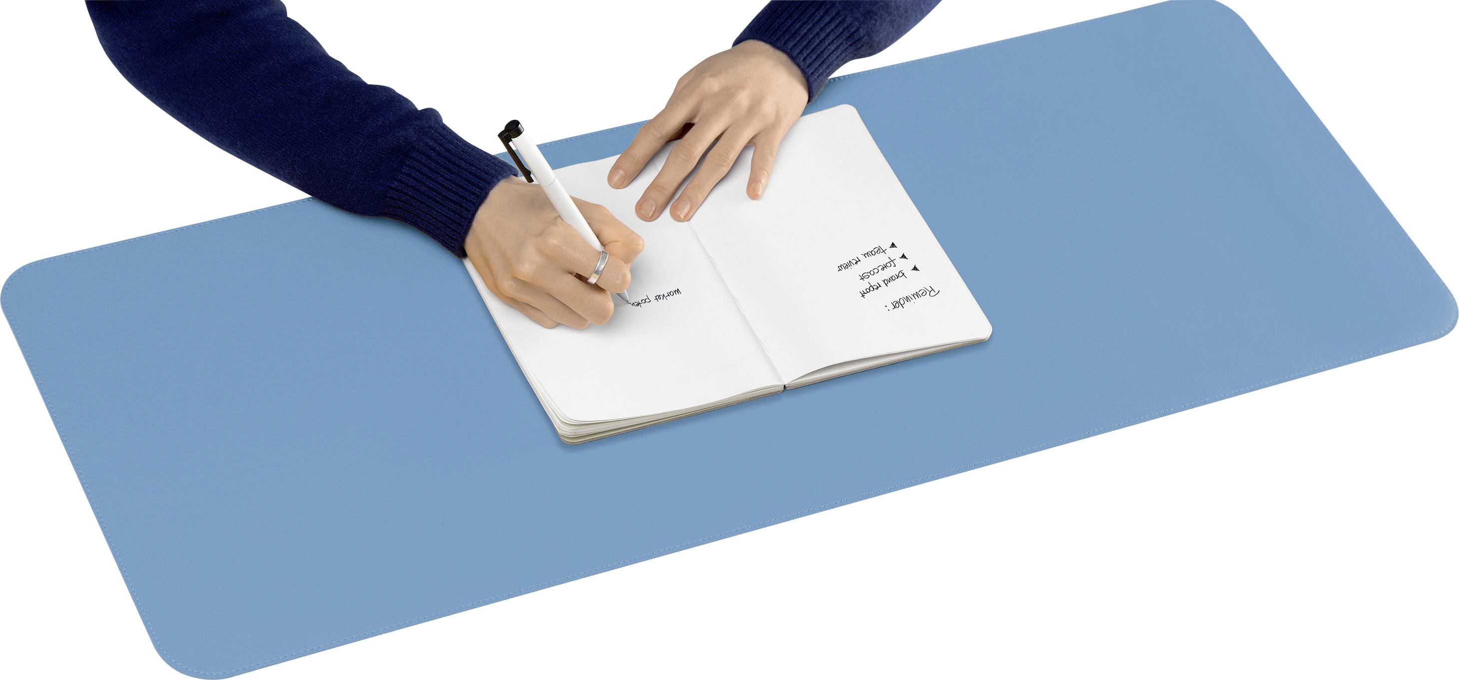 Eine Person schreibt in ein Notizbuch, das auf einer blauen Tischmatte liegt. Die Seite enthält handgeschriebene Notizen.