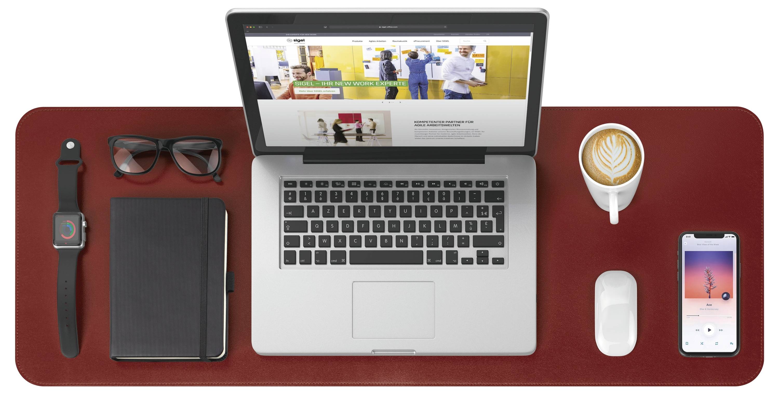 Draufsicht auf einen Arbeitsplatz mit einem offenen Laptop, einem Notizbuch, einer Uhr, einer Brille, Kaffee, einer Maus und einem Smartphone auf einer roten Schreibunterlage.