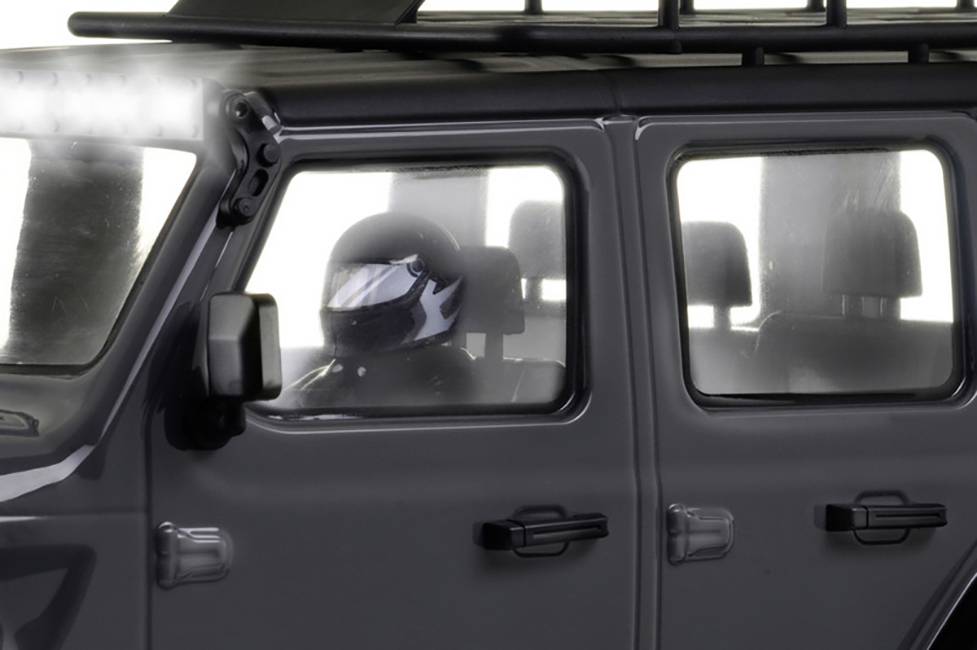 Person in einem Auto schaut durch das Fenster. Der Wagen ist grau und wirkt robust, möglicherweise für Offroad geeignet.