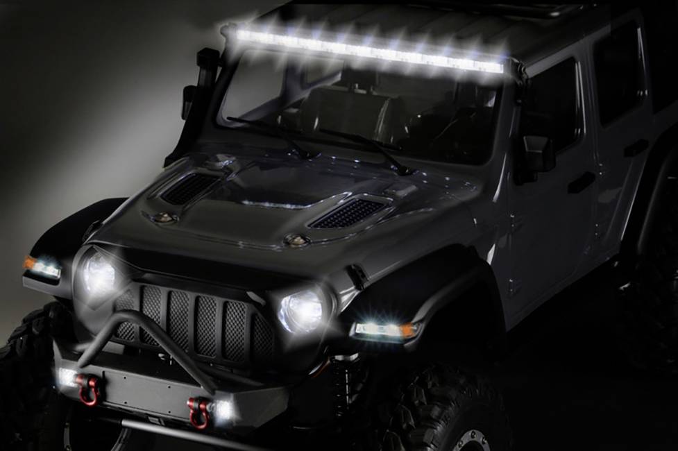 Geländewagen mit leuchtender LED-Lichtleiste auf dem Dach und eingeschalteten Scheinwerfern, steht bei schwacher Beleuchtung.