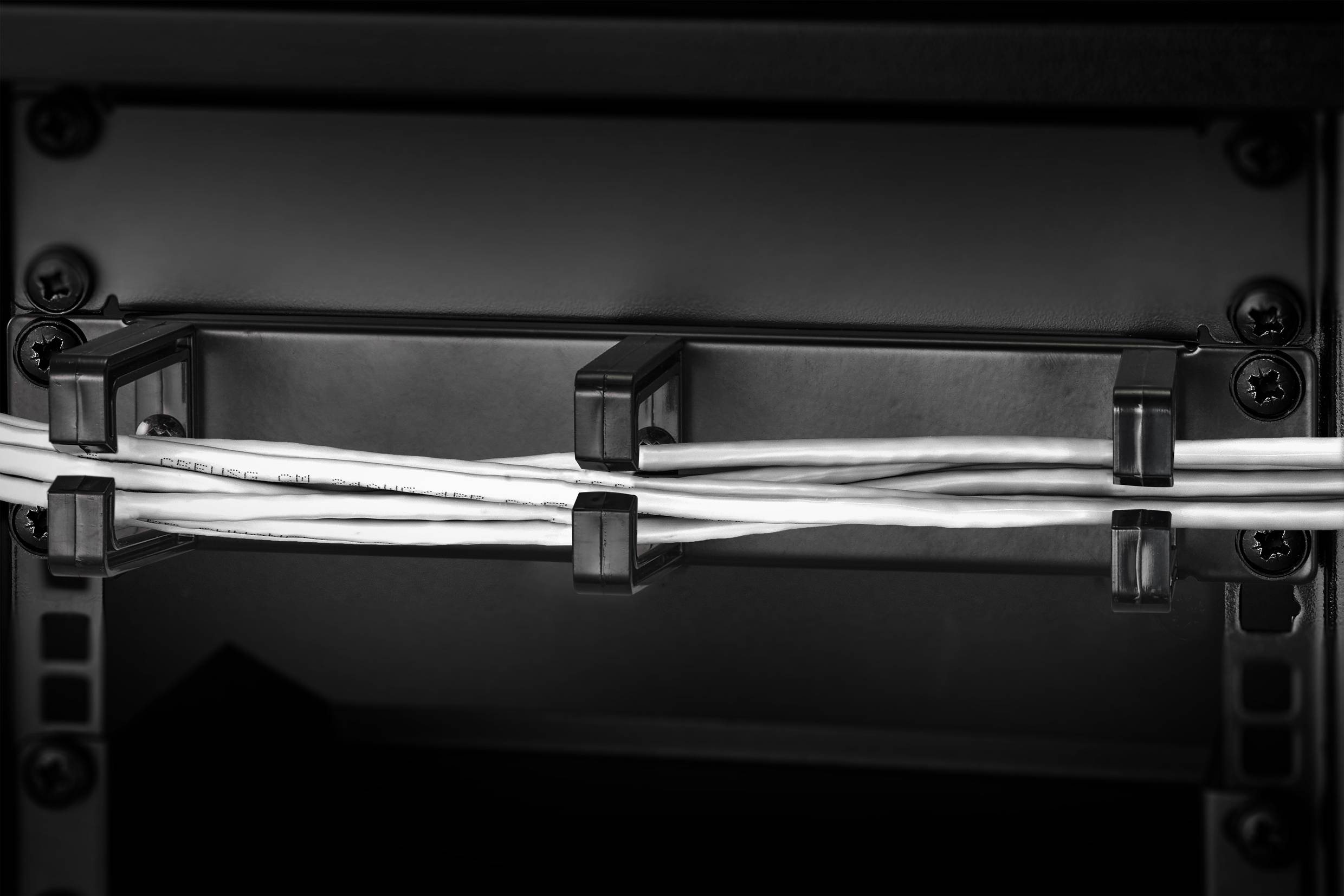 Kabel sind durch Kabelhalterungen ordentlich organisiert und verlaufen horizontal in einem dunklen, strukturellen Rahmen.