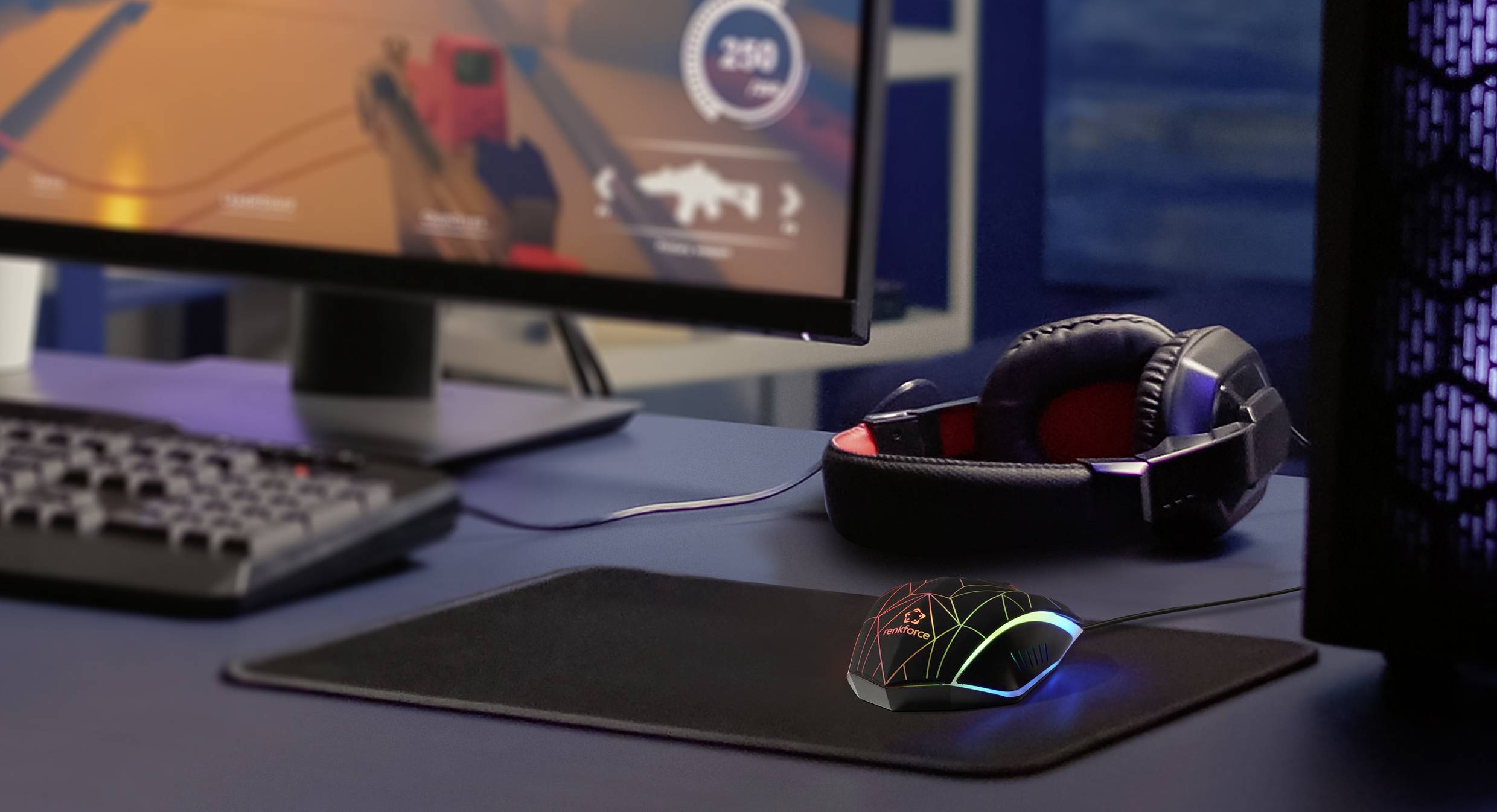 Gaming-Setup mit Monitor, Kopfhörer und beleuchteter Maus auf Tisch. Spielszene auf dem Bildschirm zeigt Action-Shooter.