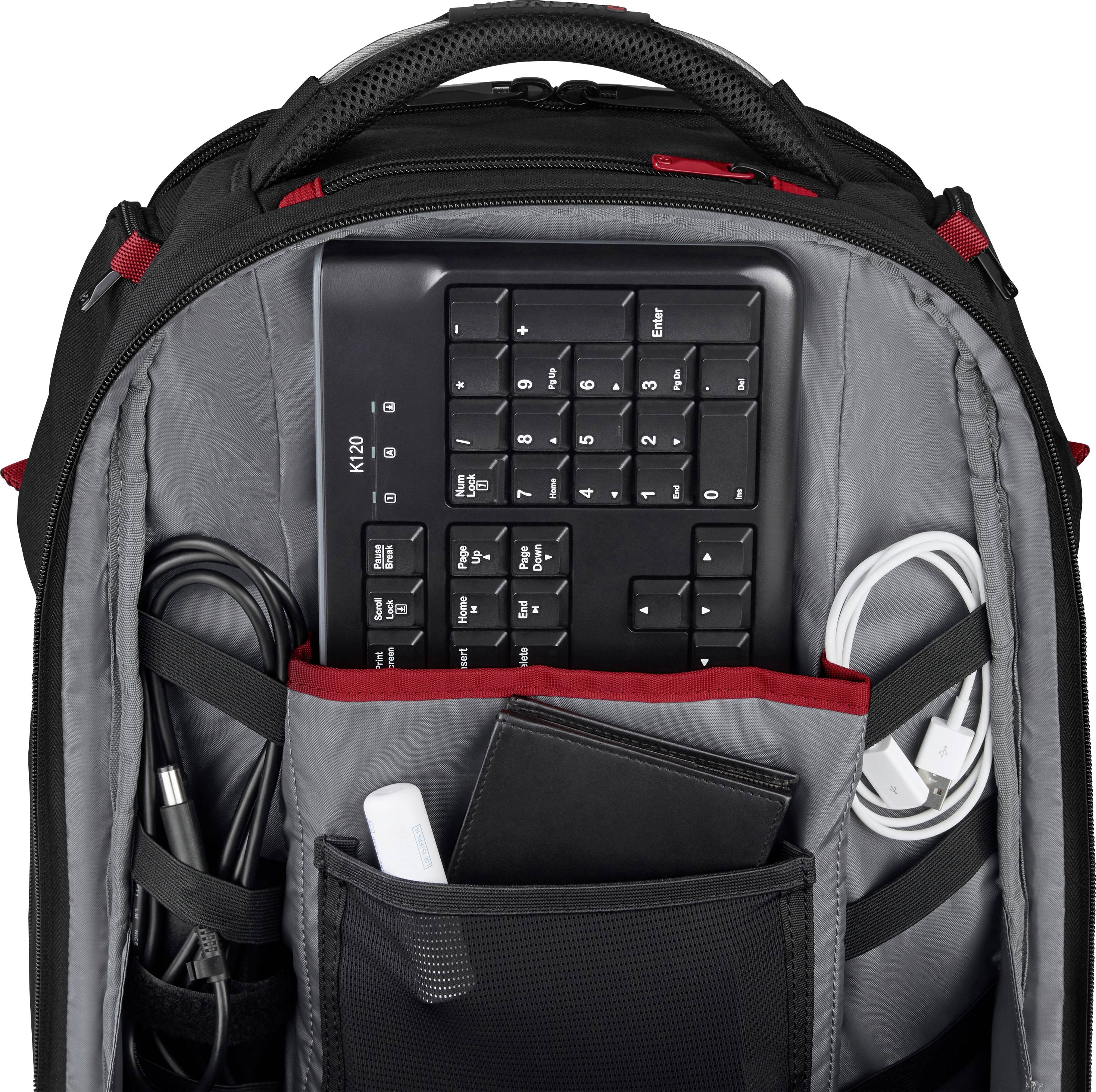 Offener Rucksack mit schwarzer Tastatur, Kabeln und einem Taschenbuch im Inneren.