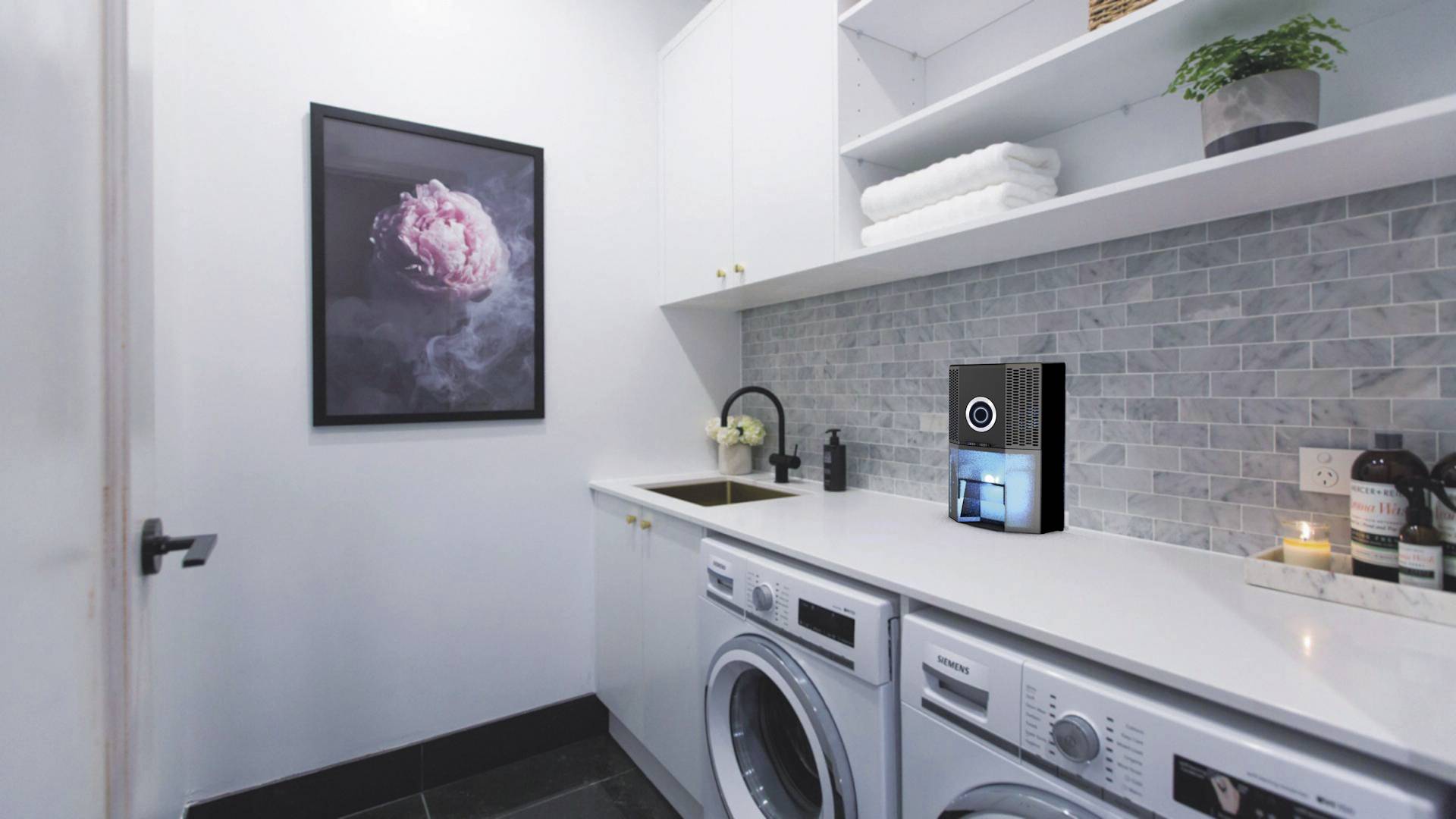 Ein Waschraum mit Waschmaschine und Trockner unter einer Arbeitsplatte. An der Wand hängt ein Bild einer rosa Blume.