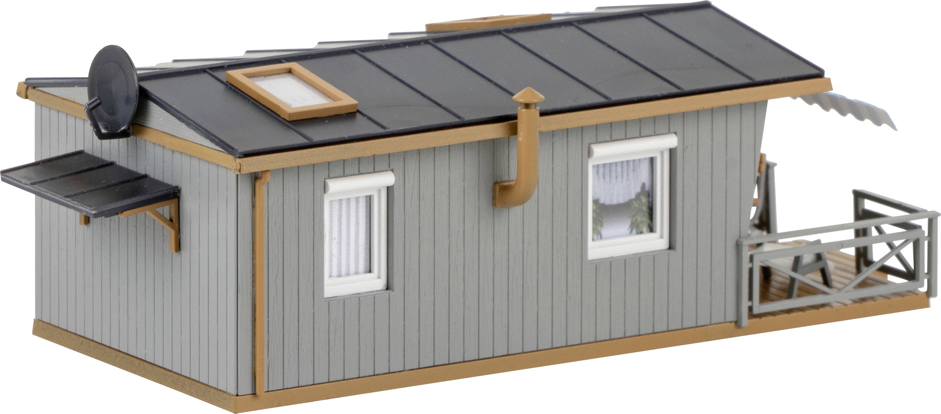 Ein graues Modell eines kleinen Gebäudes mit Flachdach, Sat-Schüssel und Fenstern. Links eine Markise, rechts ein kleiner Balkon.