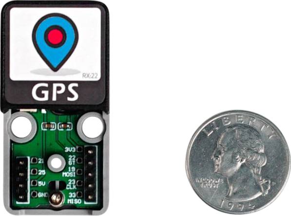 Kleiner GPS-Modul neben einer US-25-Cent-Münze zum Größenvergleich. Der Chip zeigt ein Symbol mit einem roten Punkt in einem blauen Ortungssymbol.