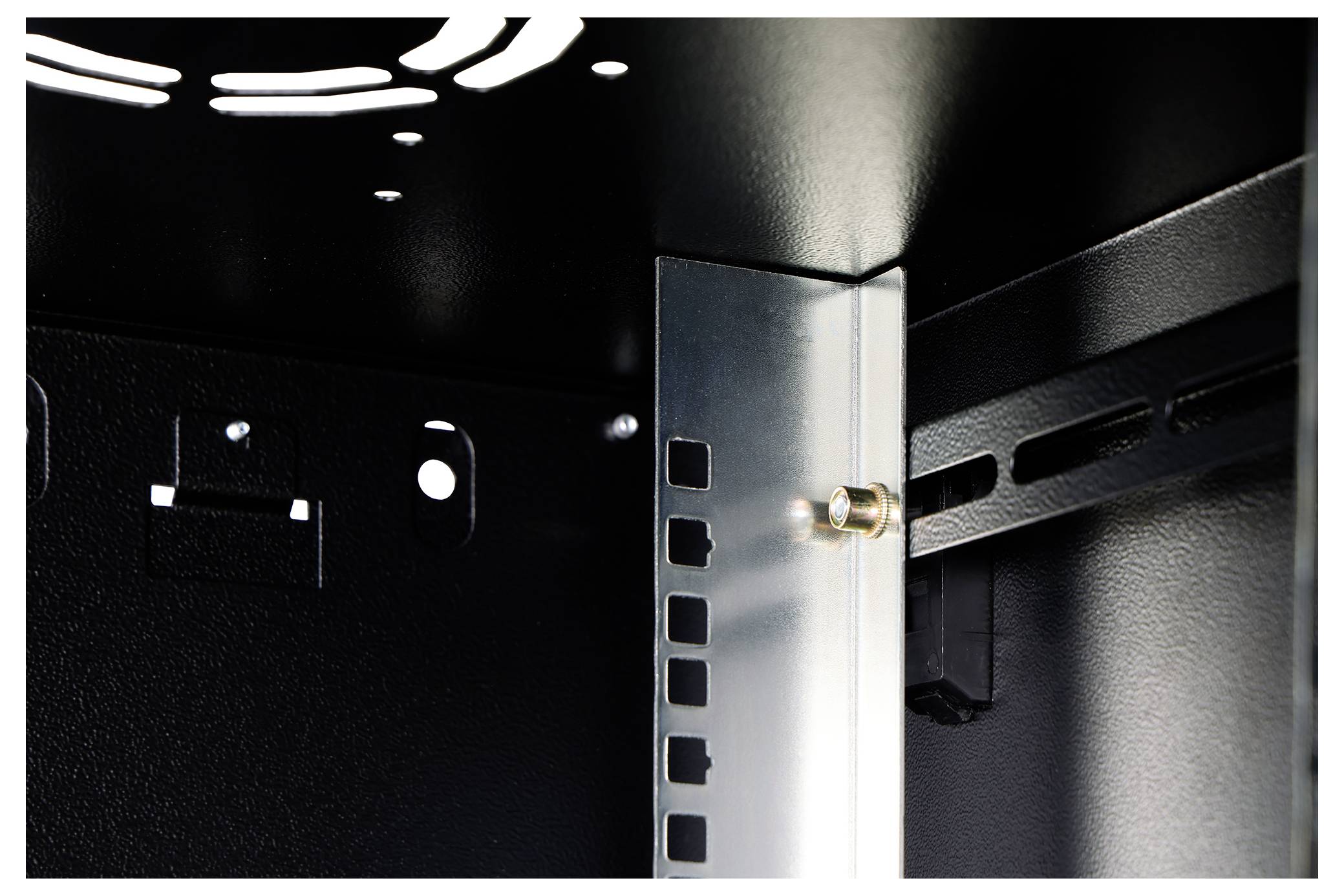 Innere Ansicht eines schwarzen Metallgestells mit einem vertikalen Metallträger und gelochten Paneelen, die eine Bolzenverbindung zeigt.