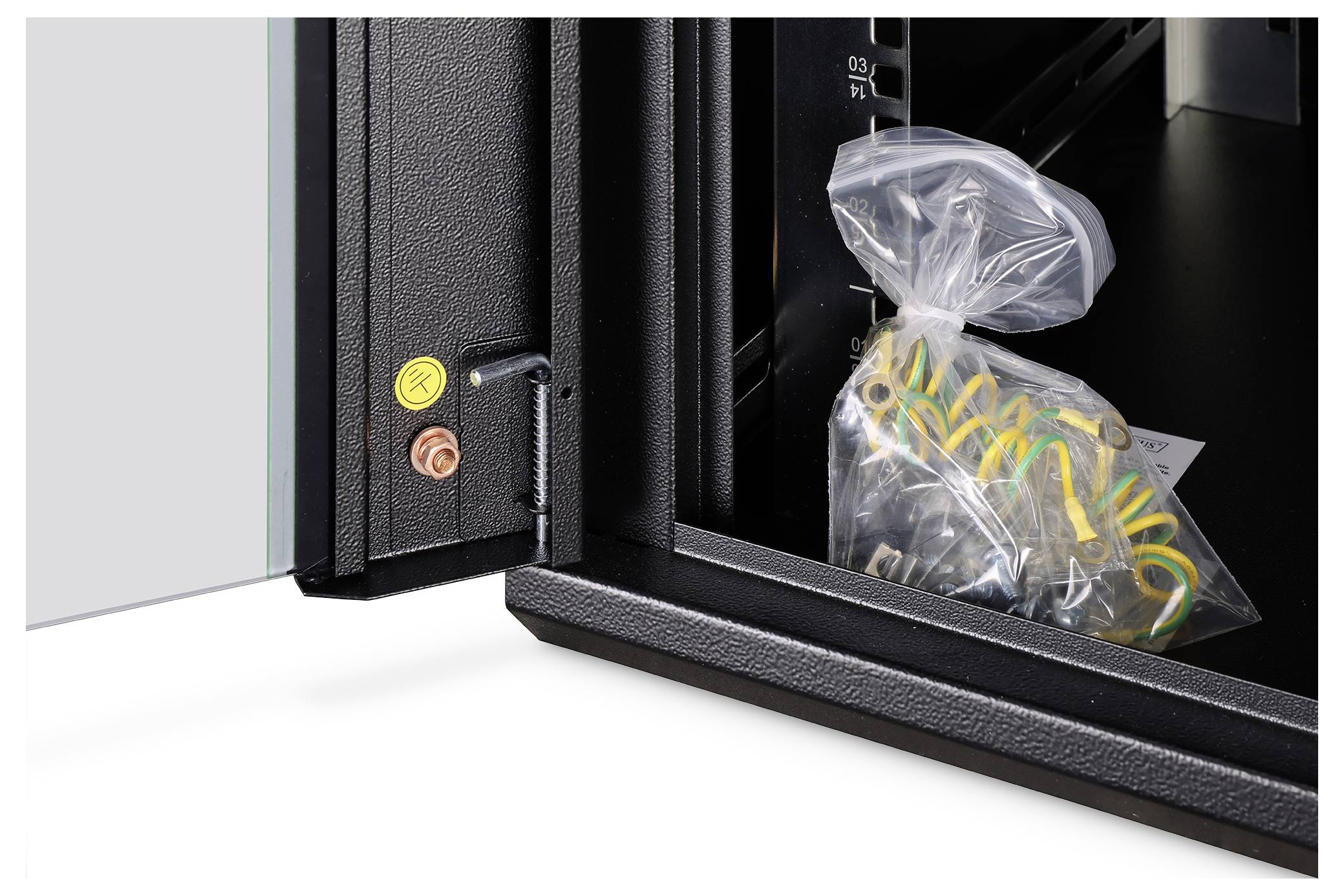 Nahaufnahme der Ecke eines Serverracks mit Erdungsanschlusspunkt und einer Plastiktüte mit Kabeln im Inneren, vor dunklem Hintergrund.