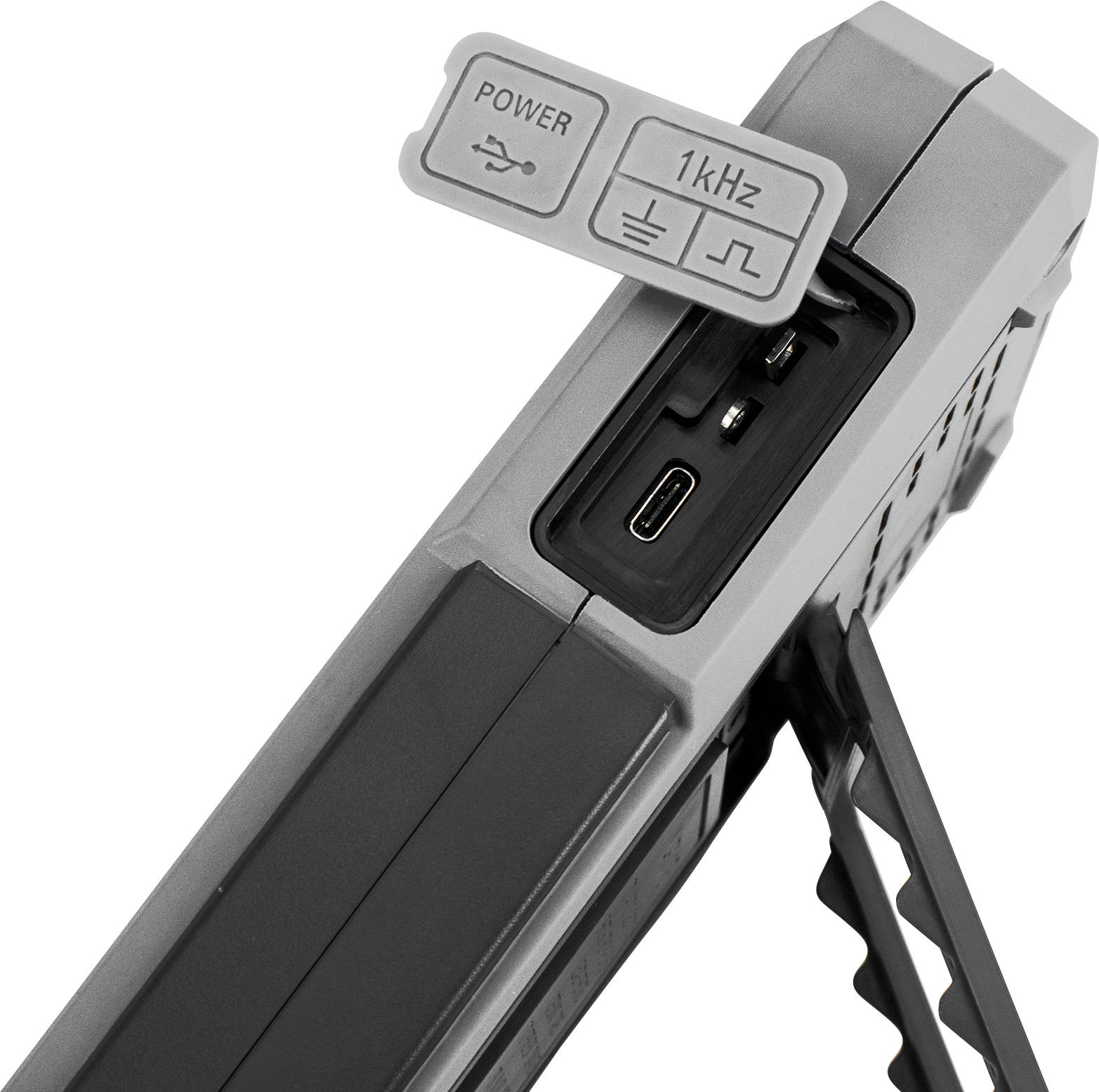 Elektronisches Gerät mit USB-Anschlüssen, einem Power-Anschluss und einem 1kHz-Schalter. Seitliche Stütze für Stabilität.