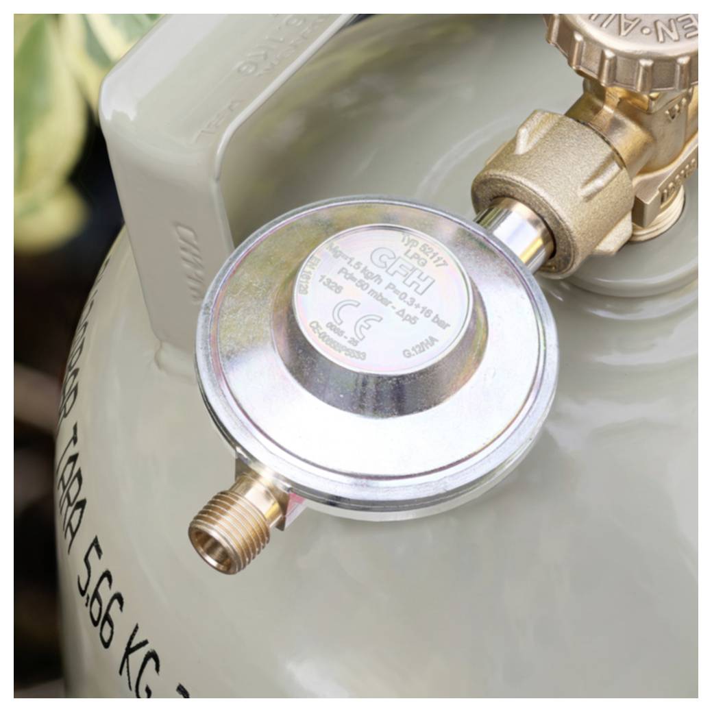 Nahaufnahme eines Gasflaschendruckregler, der an einem Ventil angebracht ist, wobei der Tankgehäuse und die Verschraubung sichtbar sind.