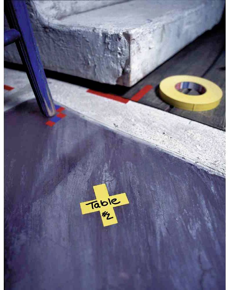 Bodenmarkierung mit gelbem Klebeband in Form eines Kreuzes, darauf steht 'Table #2'. Im Hintergrund eine Stufe und gelbes Klebeband.