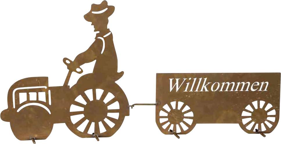 Ein aus Metall silhuettierter Traktor mit Anhänger. Der Anhänger trägt das Wort 'Willkommen'.