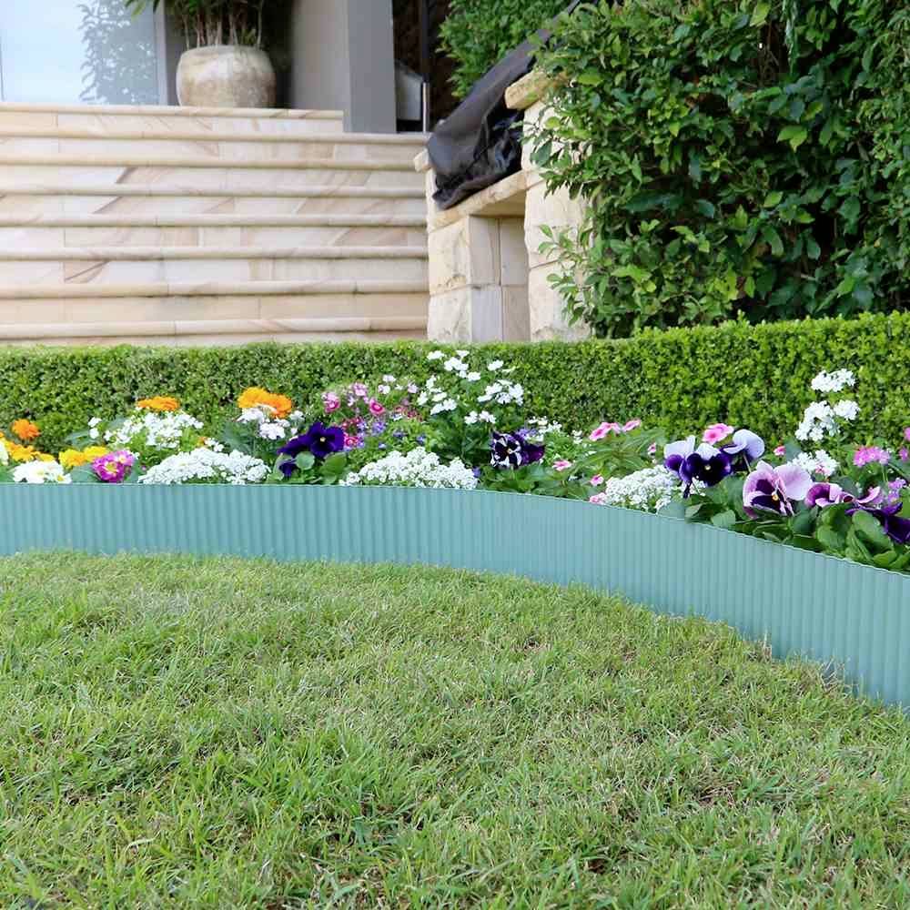Ein gepflegter Garten mit bunten Blumen, kurzem Rasen und einer Steinmauer im Hintergrund, schafft eine ruhige und einladende Atmosphäre.