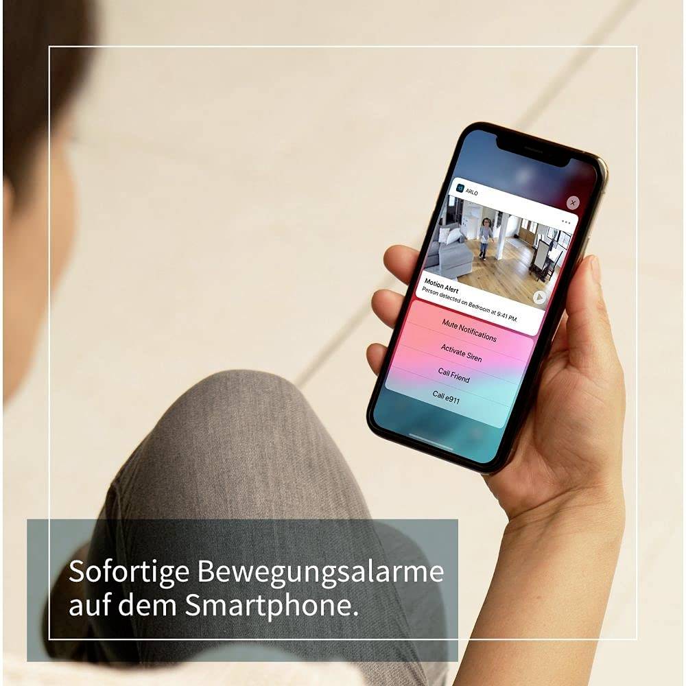 Eine Person hält ein Smartphone, das eine App mit einem Bewegungsalarm zeigt. Text: 'Sofortige Bewegungsalarme auf dem Smartphone.'