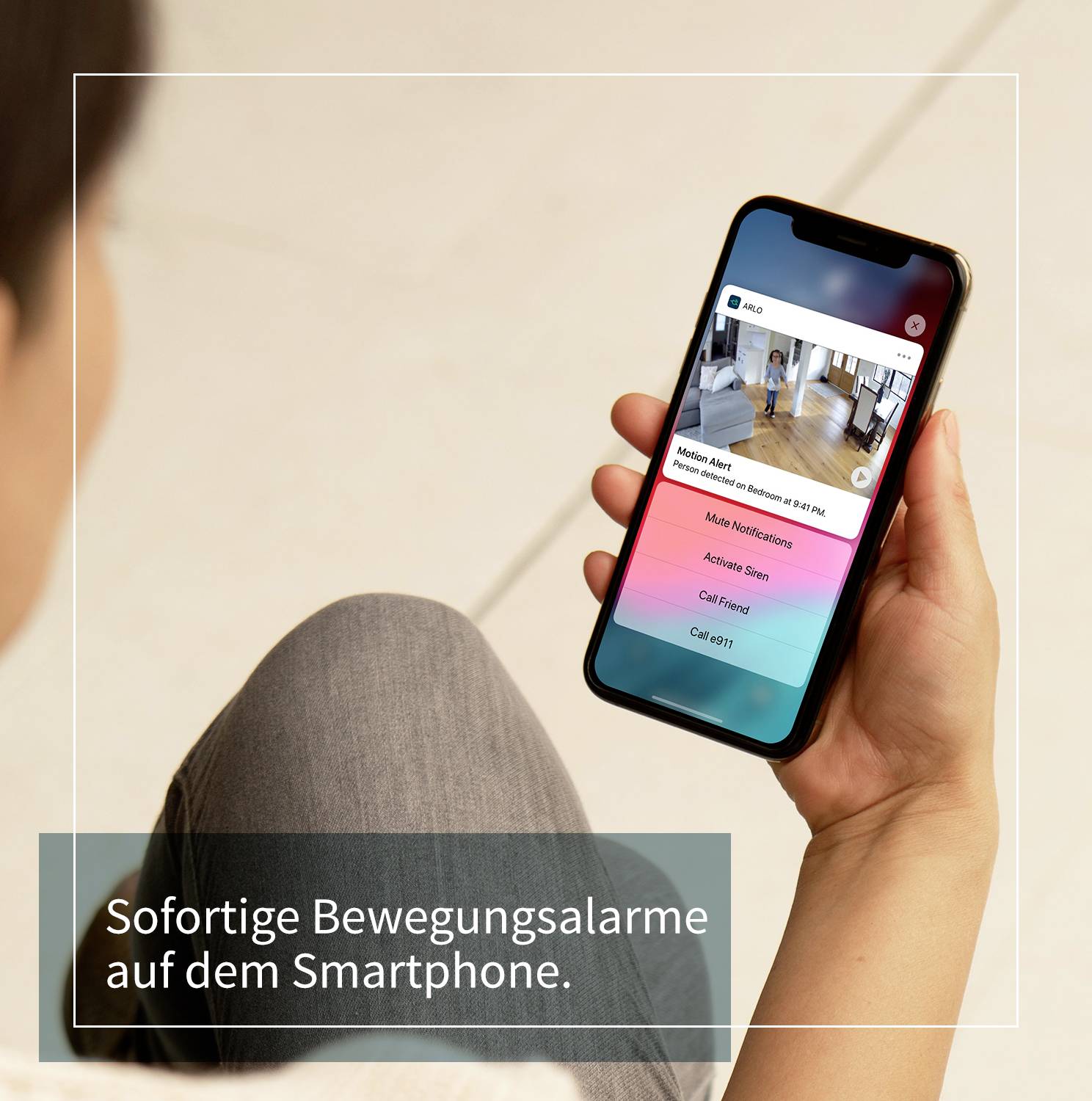 Person hält ein Smartphone mit App, die 'Haustier Foto: Siehe Aktivitäten' zeigt. Text am Bildrand: 'Sofortige Bewegungsalarme auf dem Smartphone.'