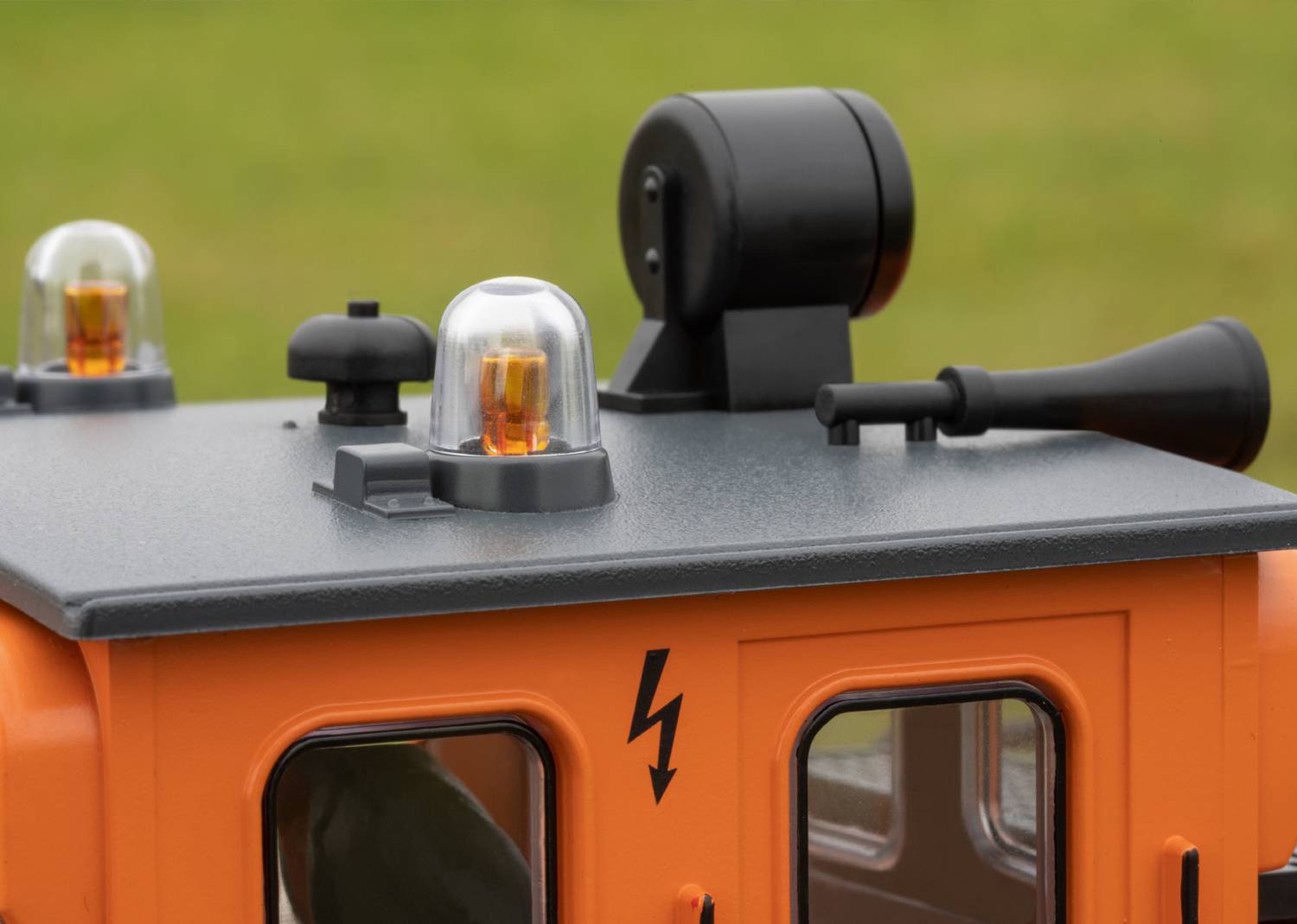 Ein orangefarbenes Modellfahrzeugdach mit Sirene und Leuchte, gekennzeichnet mit einem Blitzsymbol. Gebrauch im Freien.