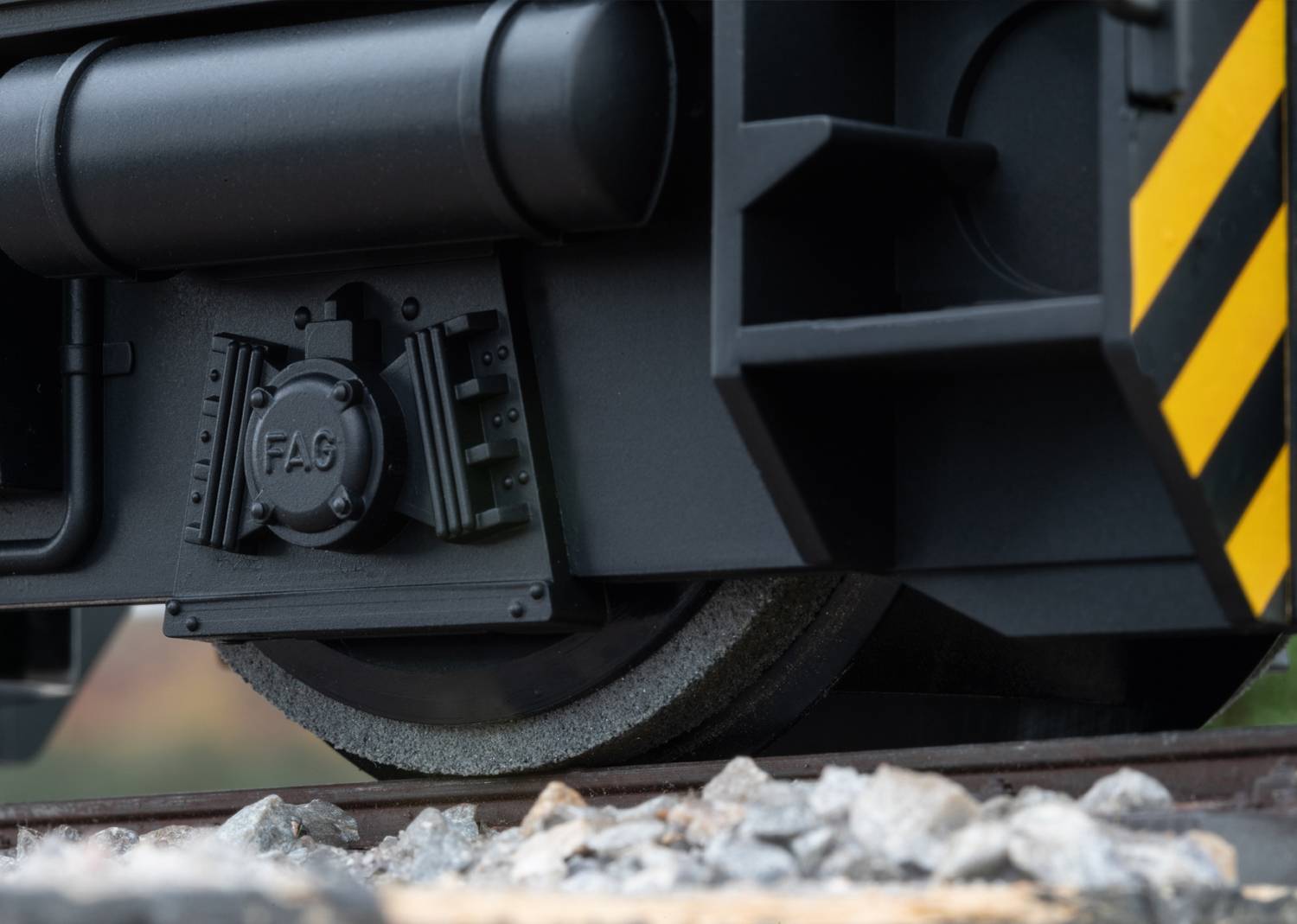 Nahaufnahme eines Zugrades auf den Gleisen. Deutliche Details der Räder und Schienen sichtbar, mit schwarzen und gelben Markierungen.