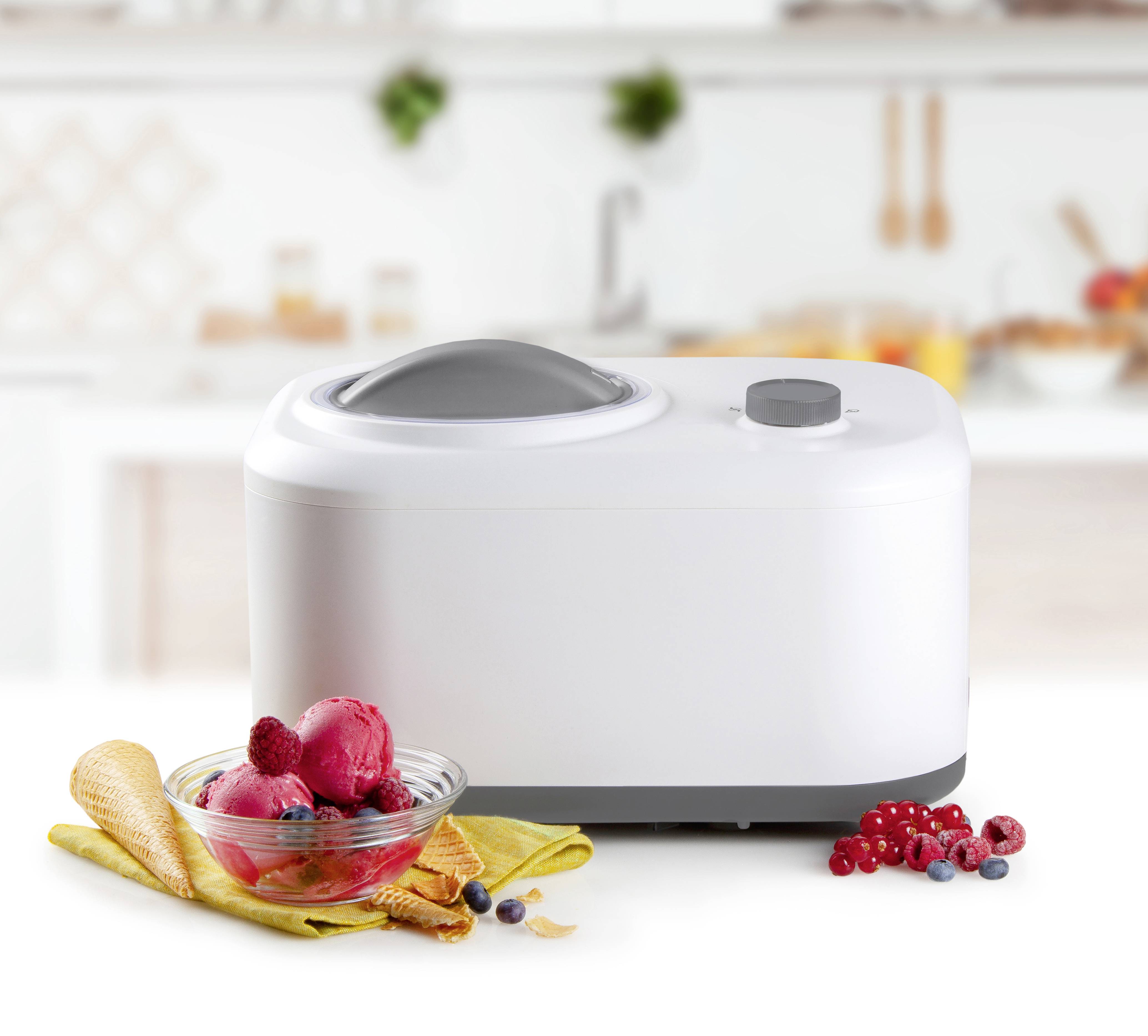 Eismaschine auf Küchentheke mit Schüssel roten Sorbets und Beeren daneben. Im Hintergrund unscharfe Küche.