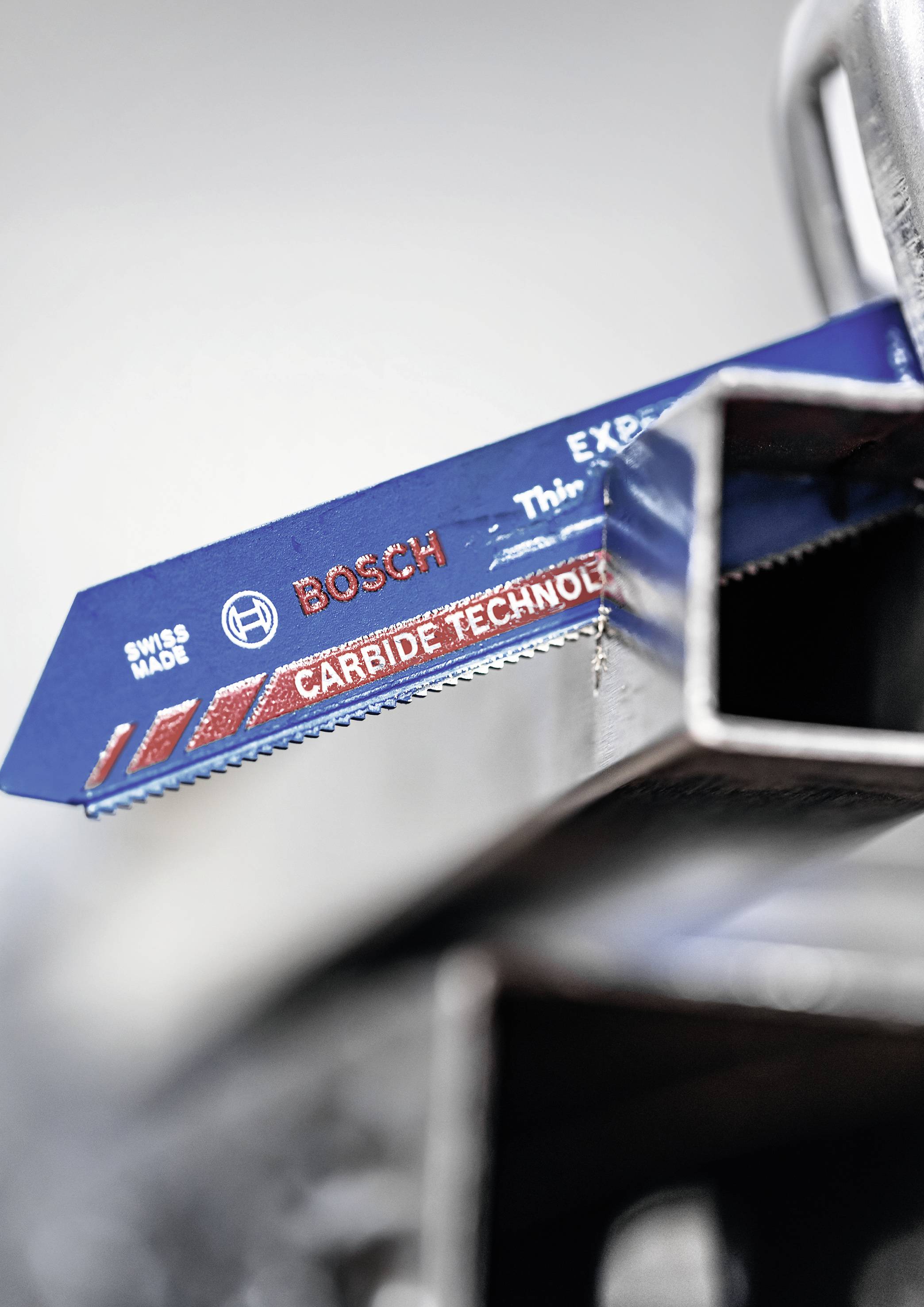 Eine blaue Metallsägeklinge mit roter Aufschrift 'BOSCH Carbide Technology' schneidet durch ein Stück Edelstahl.