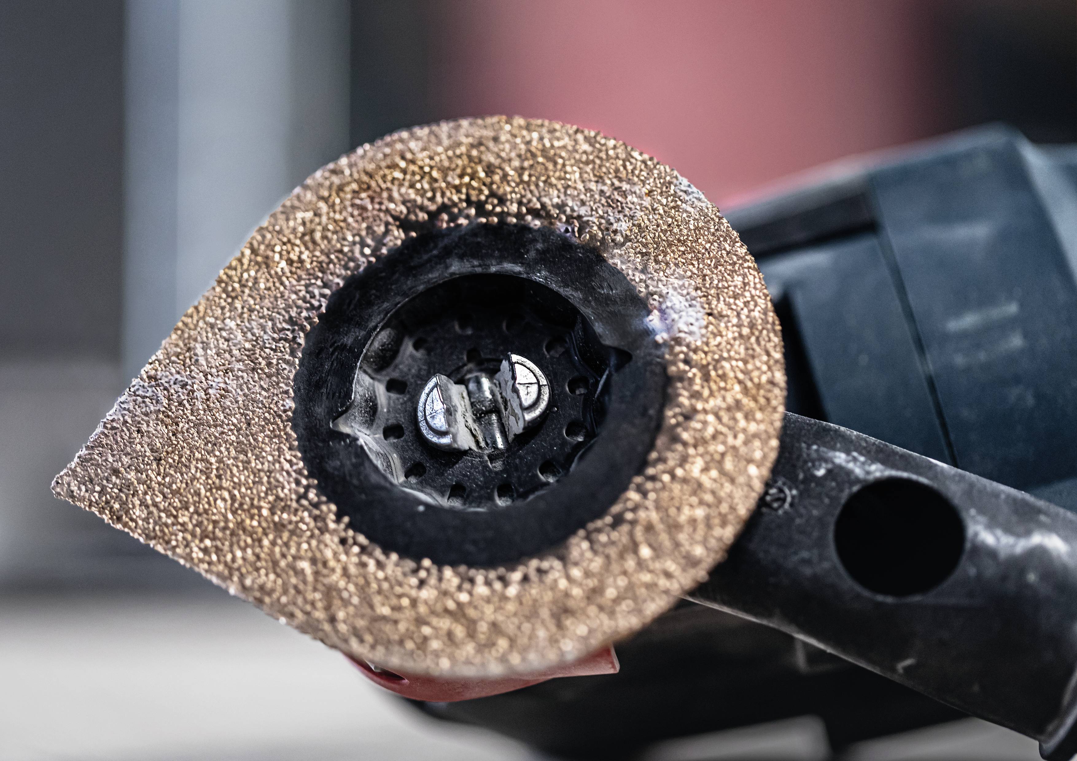 Ein Winkelschleifer mit einer grobkörnigen Schleifscheibe, offenbar in einer Werkstattumgebung, bereit zur Metallbearbeitung.