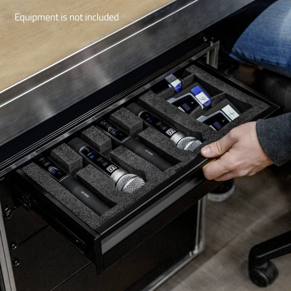 Ein Schubladenfach mit mehreren Mikrofonen in Schutzpolsterung. Eine Hand greift nach einem Mikrofon. Text auf dem Bild: 'Equipment is not included'.