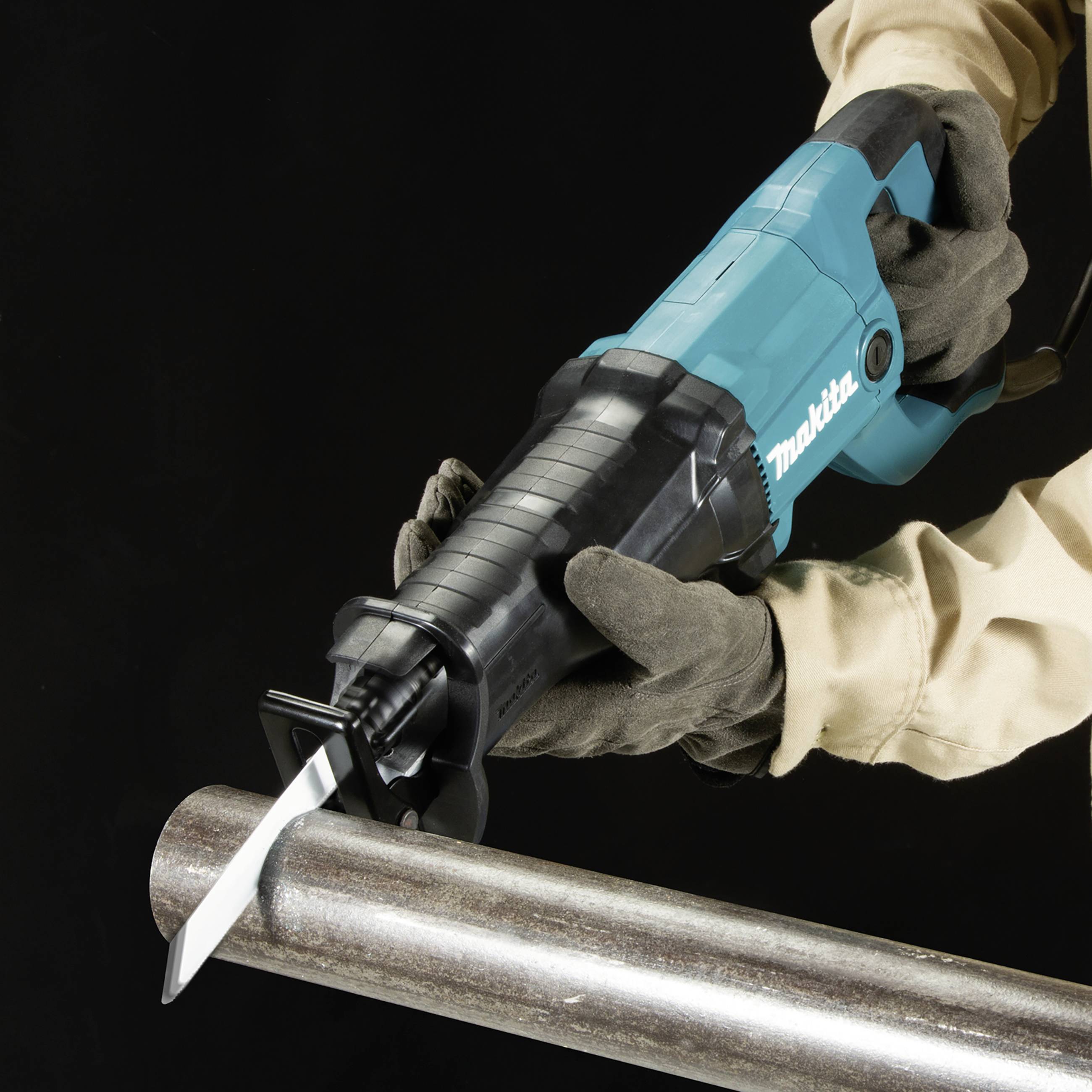 Eine Person in Arbeitshandschuhen hält eine elektrische Säge nah über einem Metallrohr bereit für eine Arbeitsausführung.