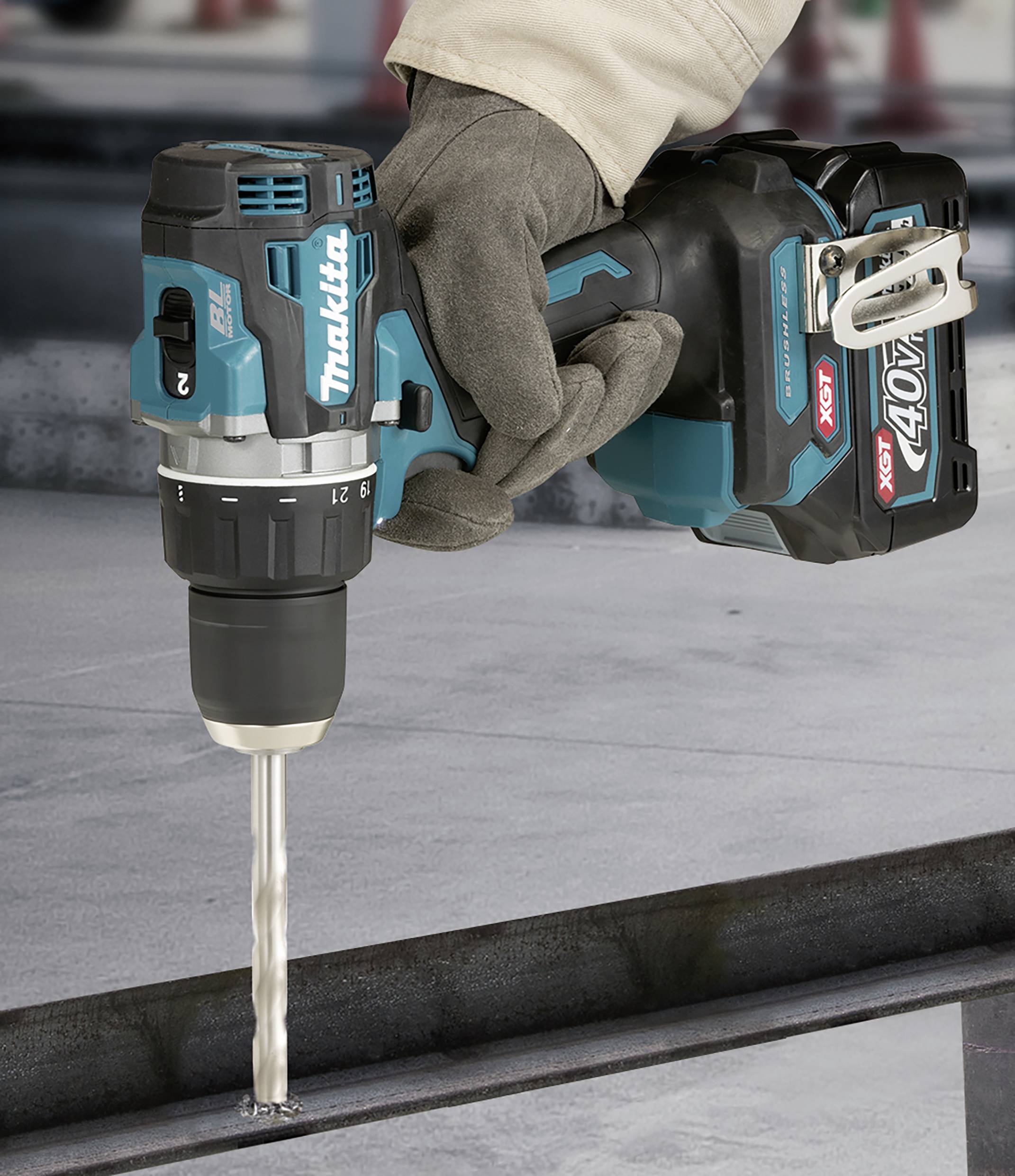 Ein Arbeiter in Handschuhen verwendet einen blauen Akkubohrschrauber, um ein Loch in ein Metallstück zu bohren.