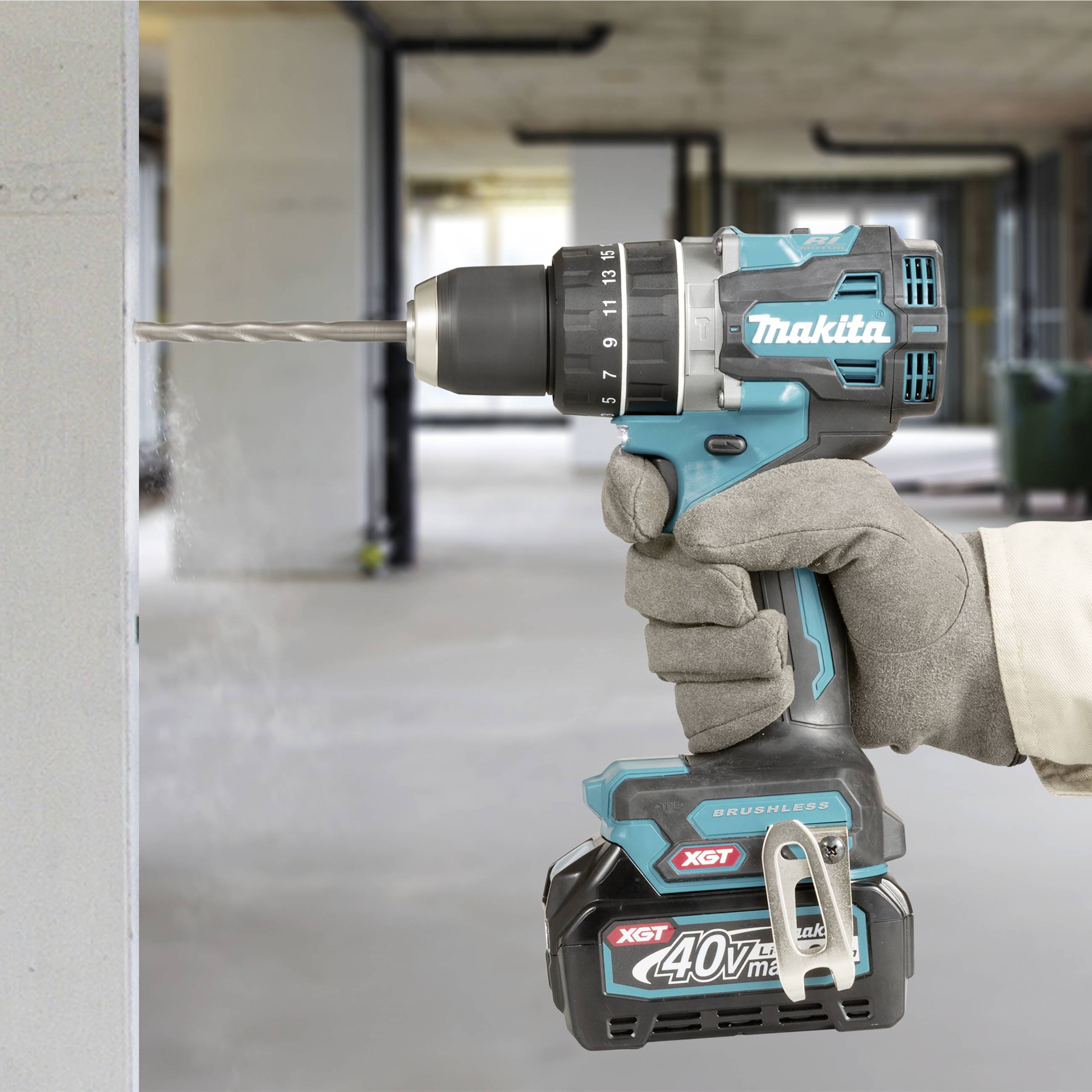 Person hält eine blaue Bohrmaschine an eine Betonwand. Die Maschine wirbelt Staub auf und hat einen 40V-Akku.