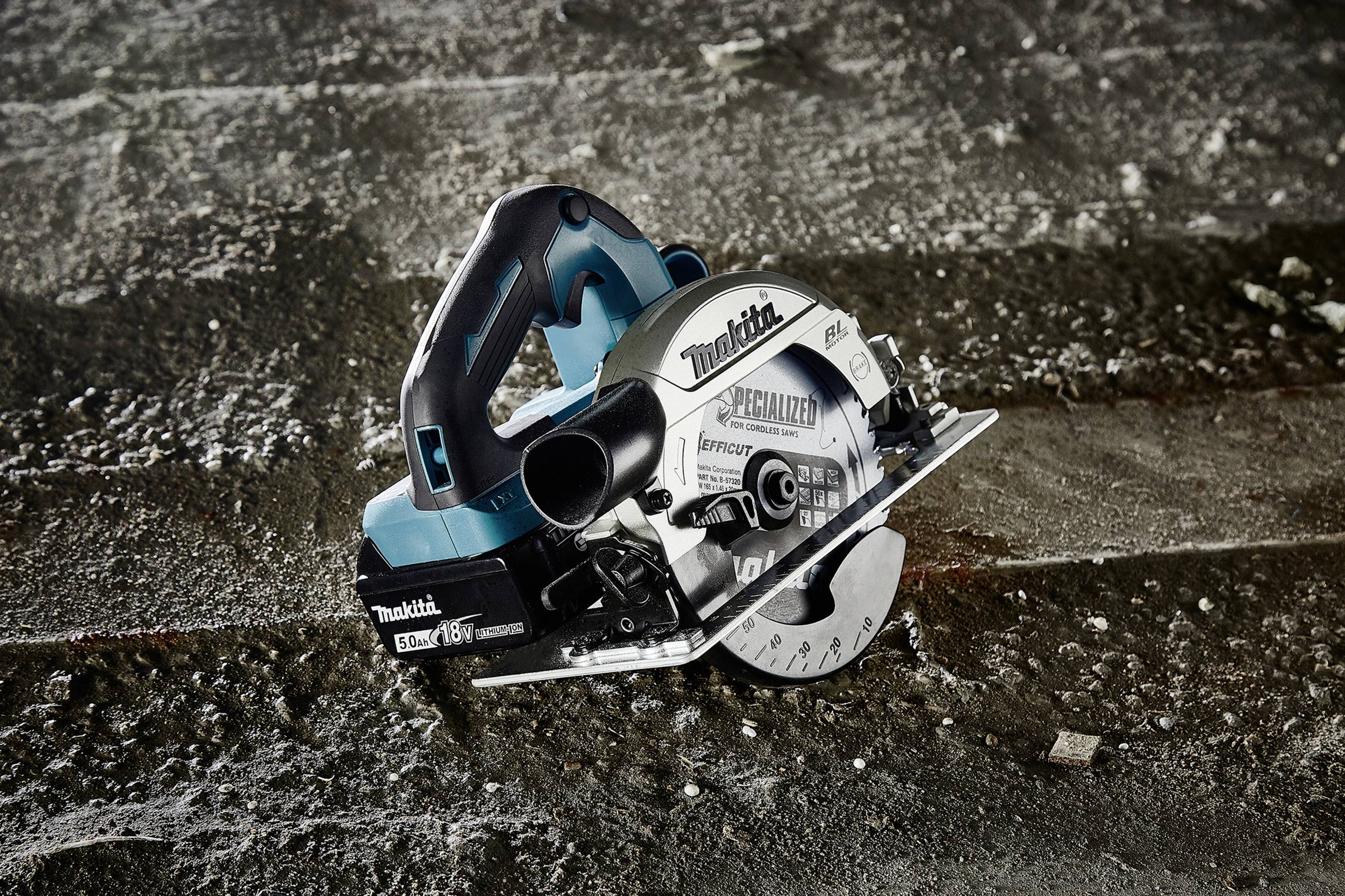 Eine Handkreissäge liegt schräg auf einem Betonboden. Die Säge hat ein blau-schwarzes Gehäuse und ein sichtbares Sägeblatt.