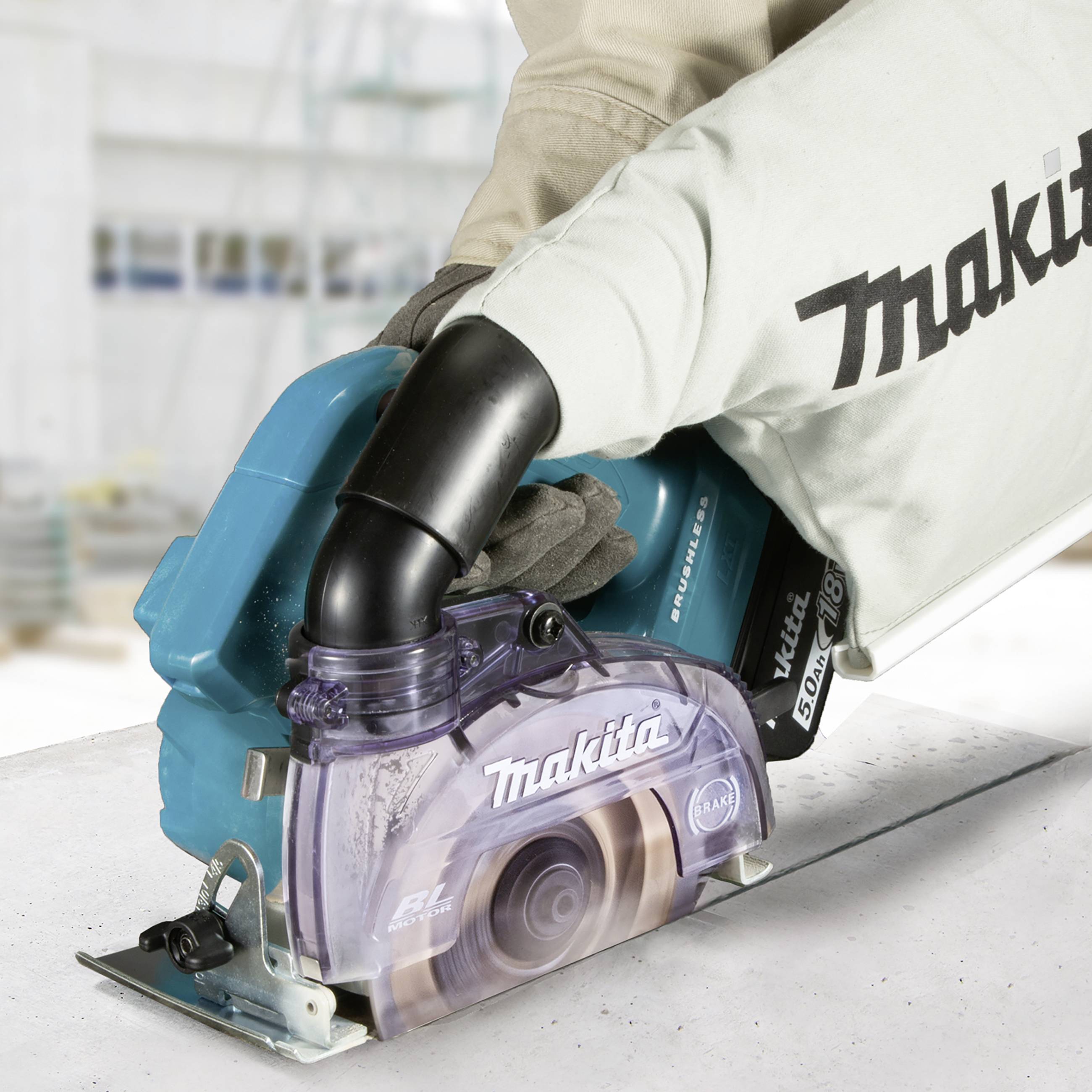 Eine Person arbeitet mit einer blauen Makita Handkreissäge auf einer weißen Arbeitsplatte.