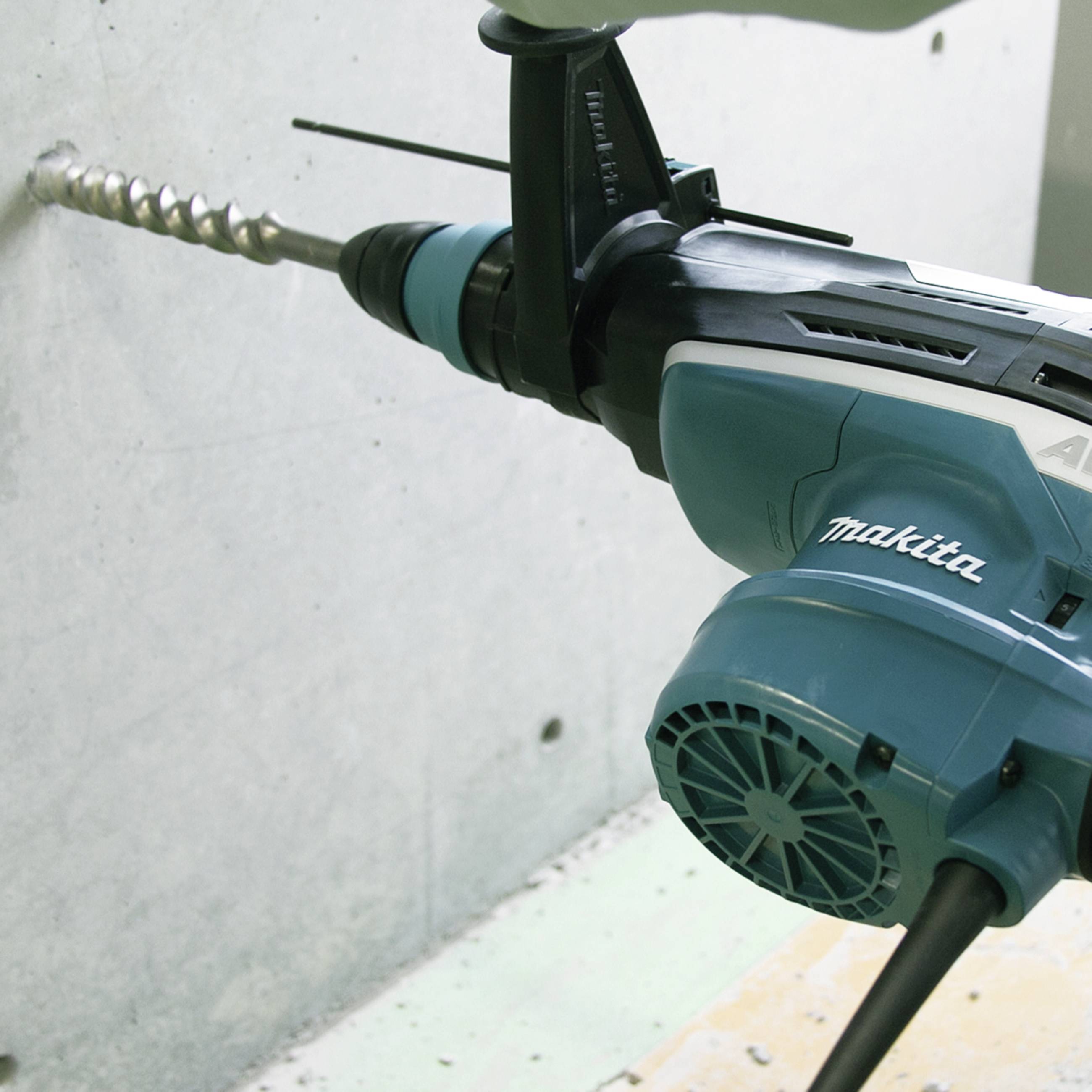 Eine blaue Bohrmaschine der Marke Makita bohrt in eine Betonwand.