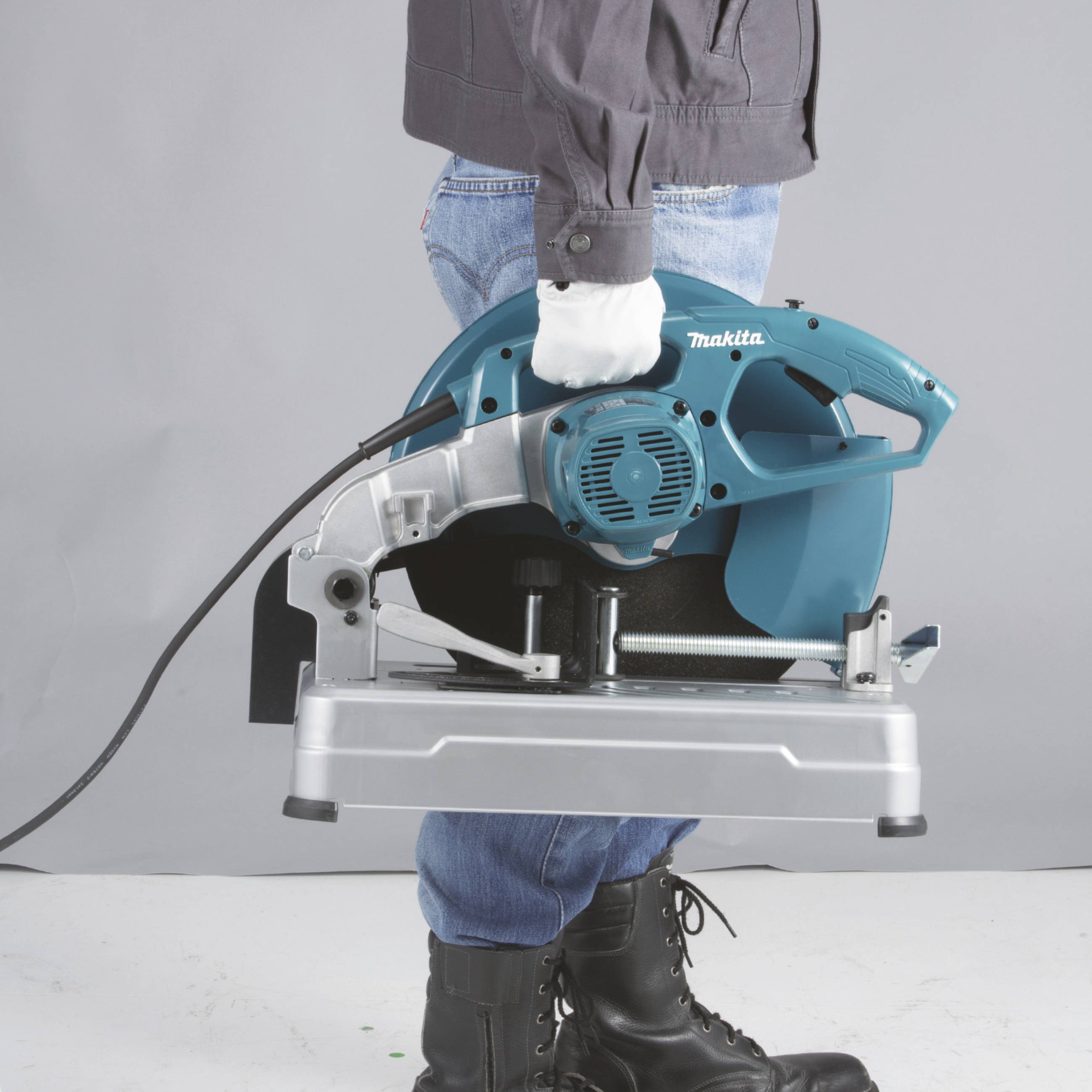 Eine Person hält eine tragbare, blaue Elektrosäge von Makita, bereit für den Einsatz.