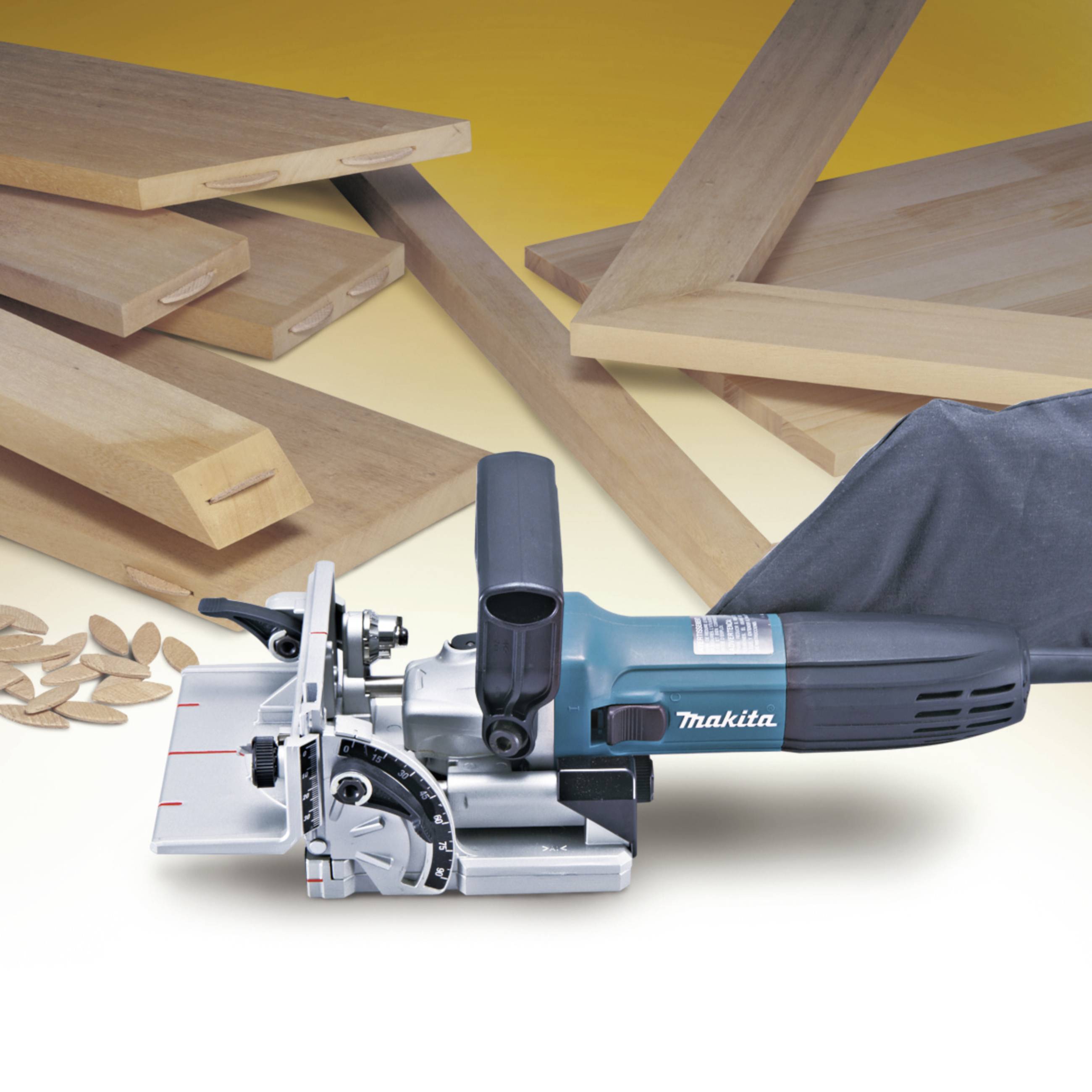 Elektrische Holznutfräse vor mehreren Holzplatten und Verbindungsstücken, die zur Herstellung von Nut- und Federverbindungen verwendet werden.