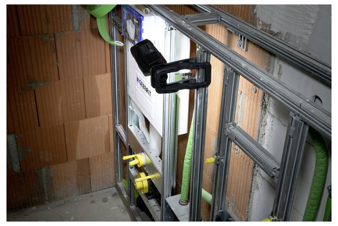 Teilweise errichtete Innenwandverkleidung mit Metallständern, Isolierung und grünen Rohren um eine eingebaute mechanische Anlage mit gelben Ventilen.
