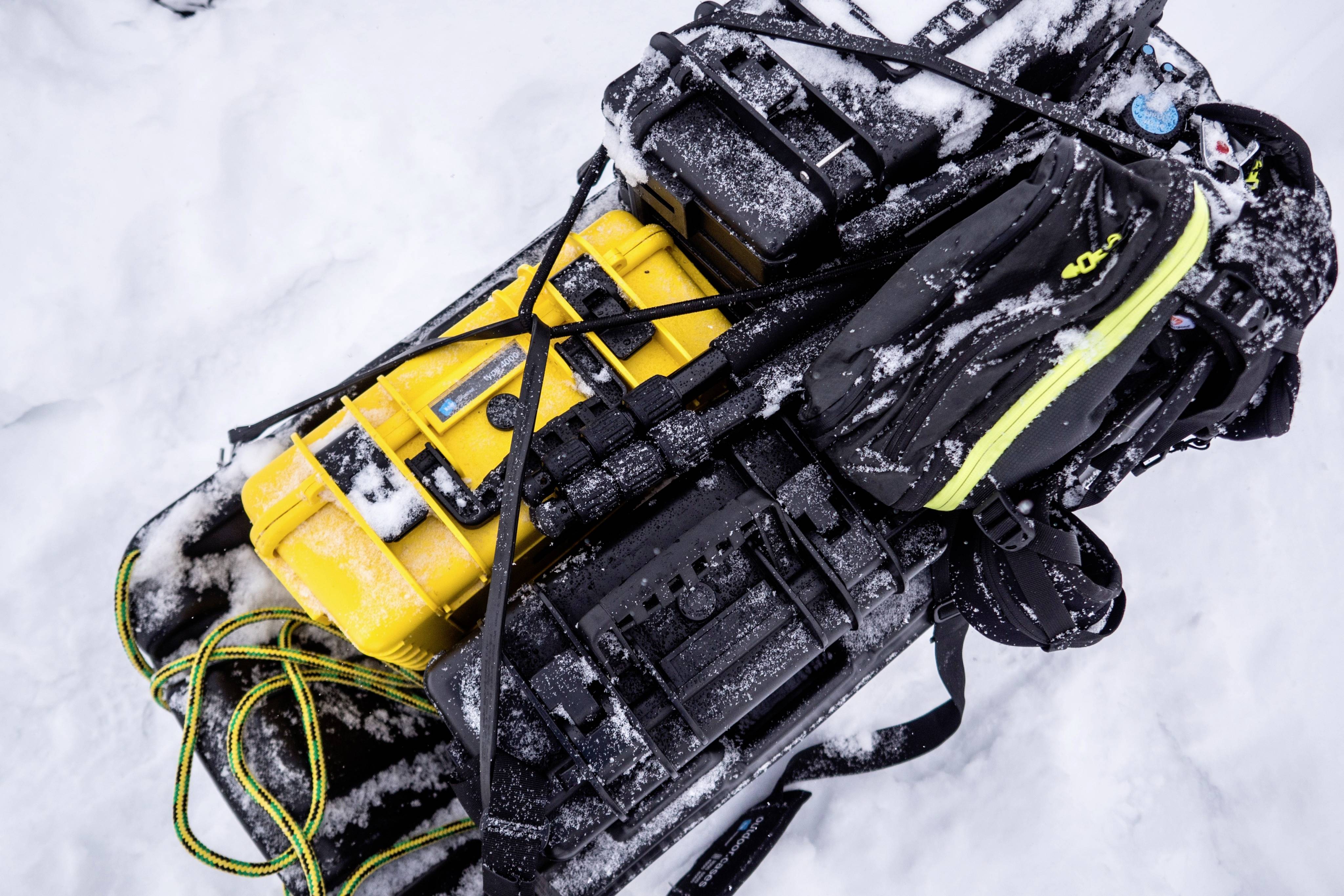 Gepackte Ausrüstung auf einem Schlitten im Schnee, umfasst gelbe und schwarze Taschen, gesichert mit Gurten, zeigt Vorbereitungen für Expeditionen.