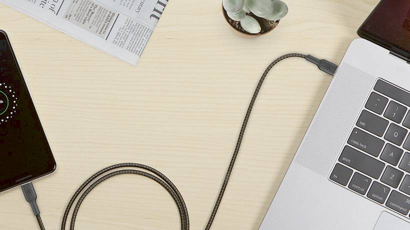Smartphone mit einem Ladekabel verbunden, das an einen Laptop angeschlossen ist; Ladeanzeige auf dem Smartphone-Bildschirm.