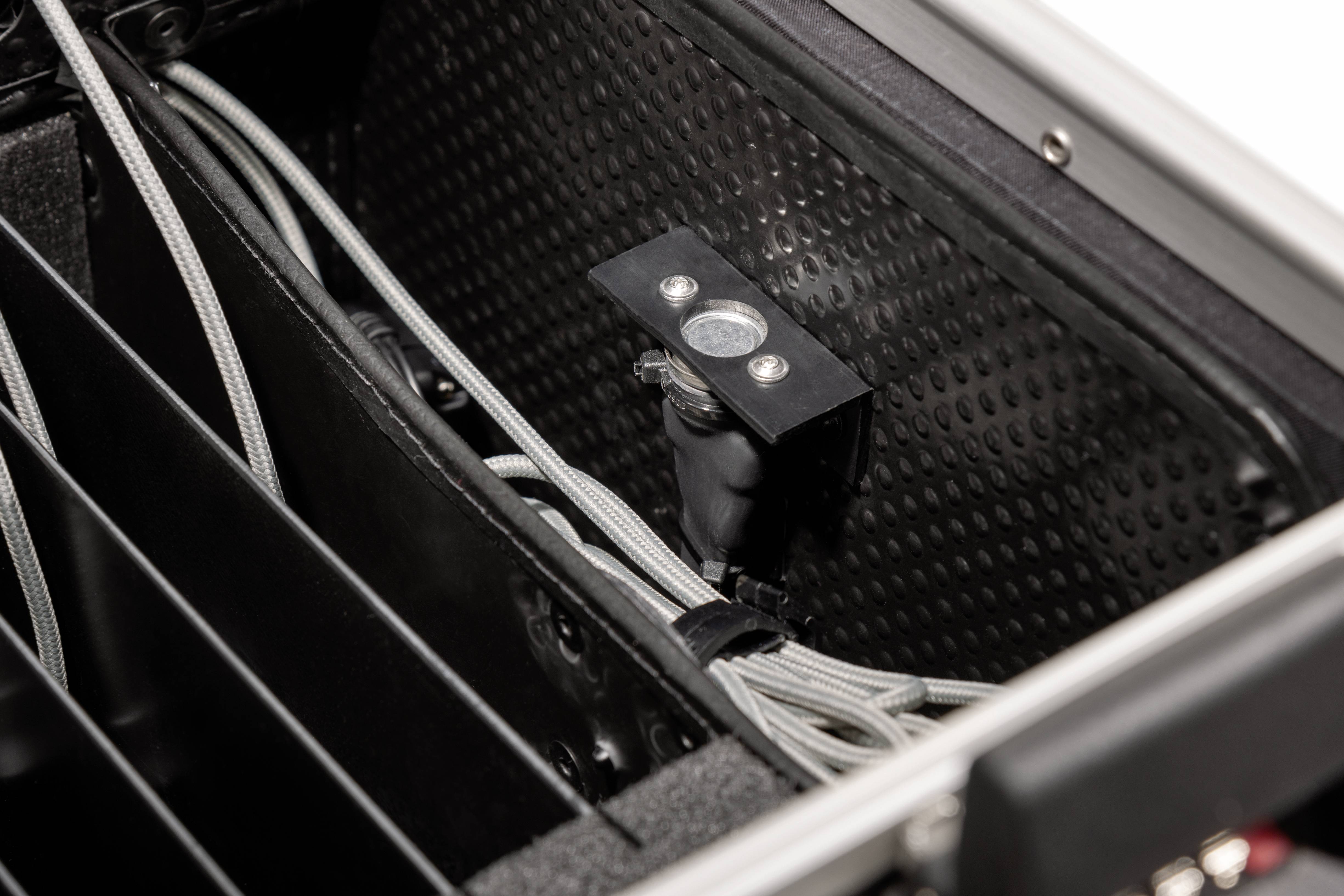 Innenansicht eines Technikgehäuses zeigt Kabelmanagement und ein montiertes Objektiv, das für optische Anwendungen verwendet wird.