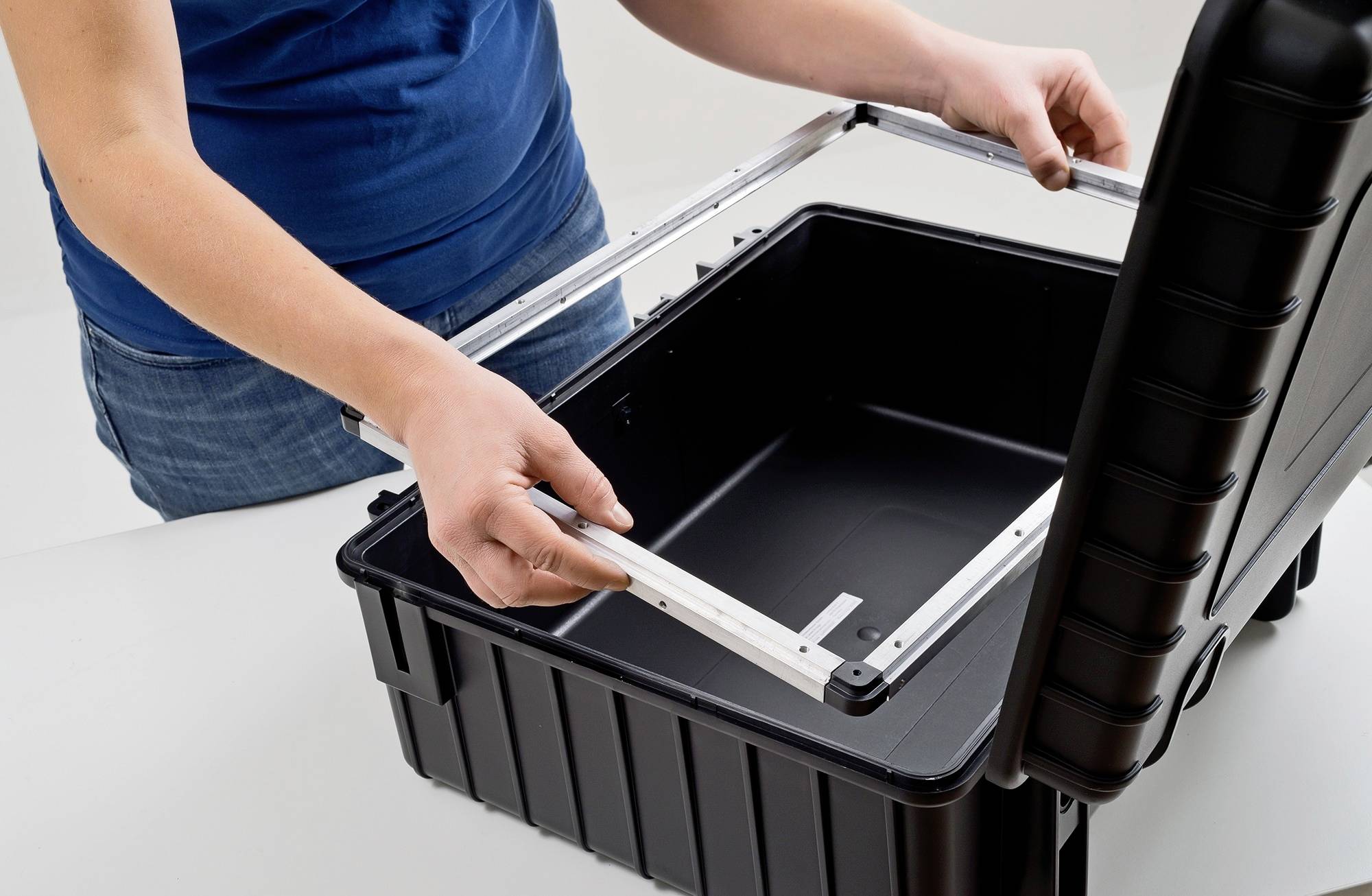 Eine Person montiert einen Metallrahmen in einen offenen schwarzen Werkzeugkoffer.