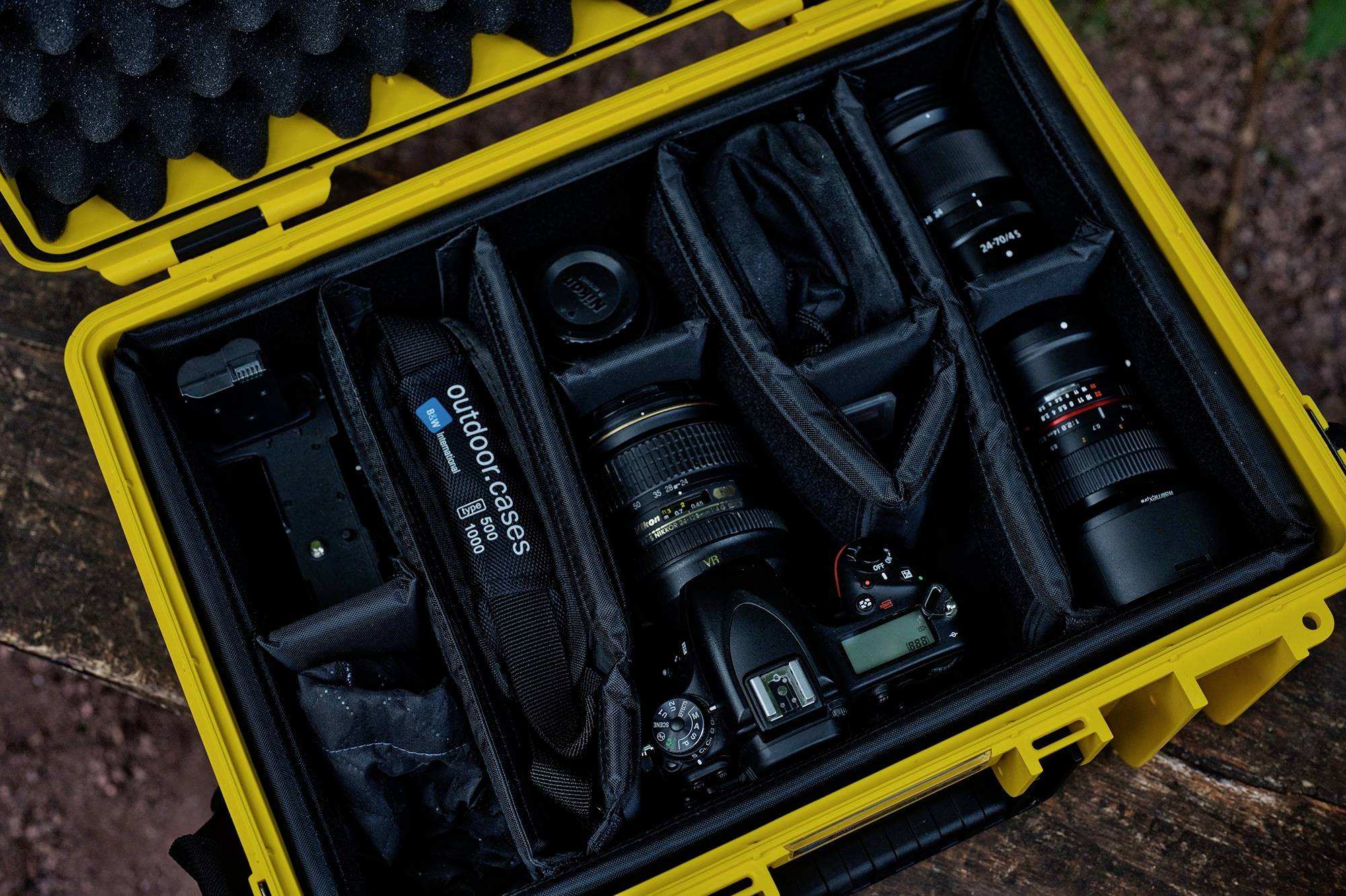 Foto eines gelben Transportkoffers, der eine professionelle Kamera, mehrere Objektive und Zubehör sicher in gepolsterten Fächern verstaut.