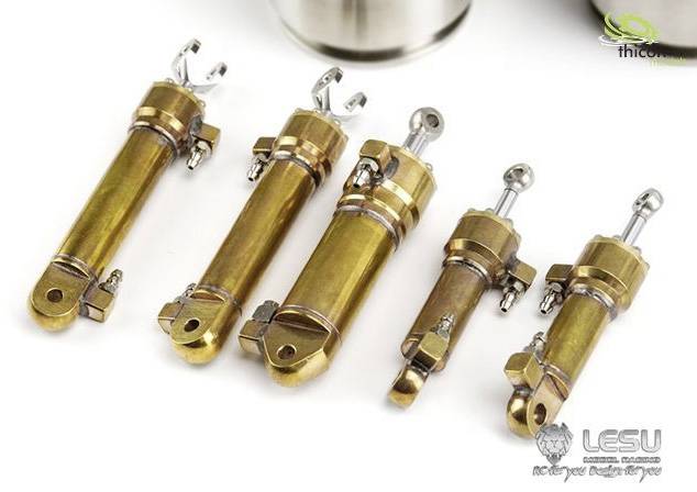 Fünf goldene Metallzylinder mit Gelenken und Schrauben, auf einer weißen Oberfläche arrangiert. Technische Bauteile für Modellbau.