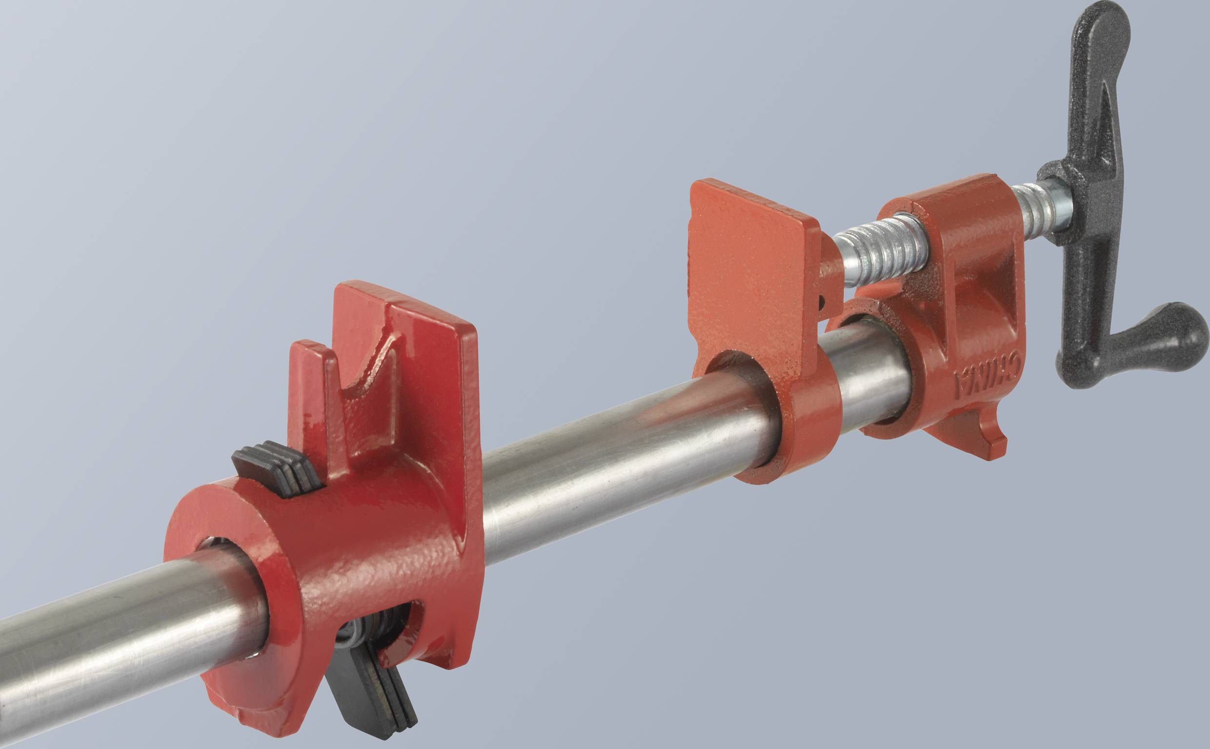 Ein rotes Rohrspannwerkzeug mit Schraubmechanismus vor einem grauen Hintergrund.
