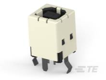 Schwarzer quadratischer Mini-Drucktaster, montiert auf einem weißen Kunststoffgehäuse, mit zwei festen Beinchen.