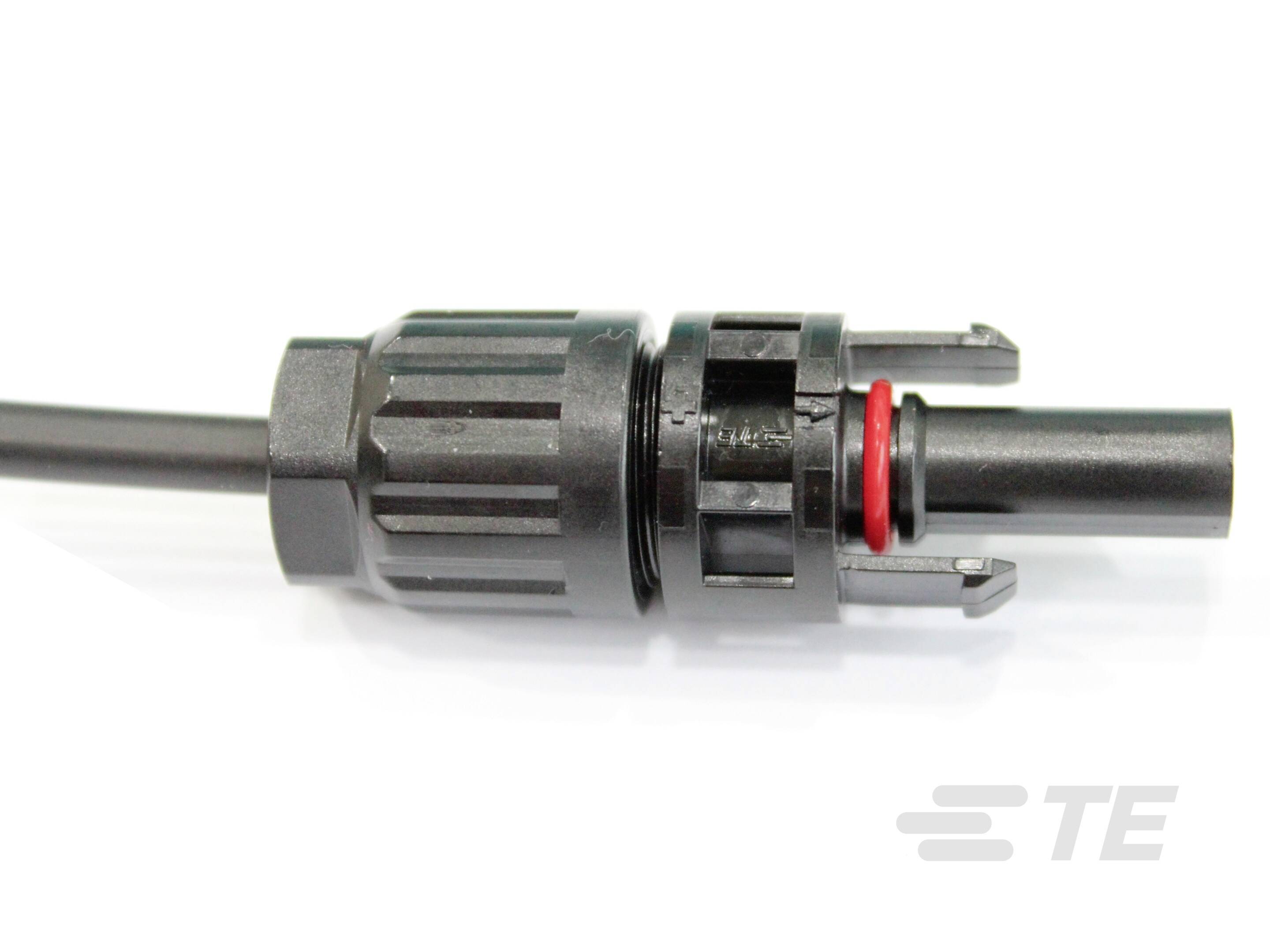 Ein schwarzer, zylindrischer Steckverbinder mit einem schwarzen Kabel und einem roten Dichtring, liegt auf einer weißen Oberfläche.