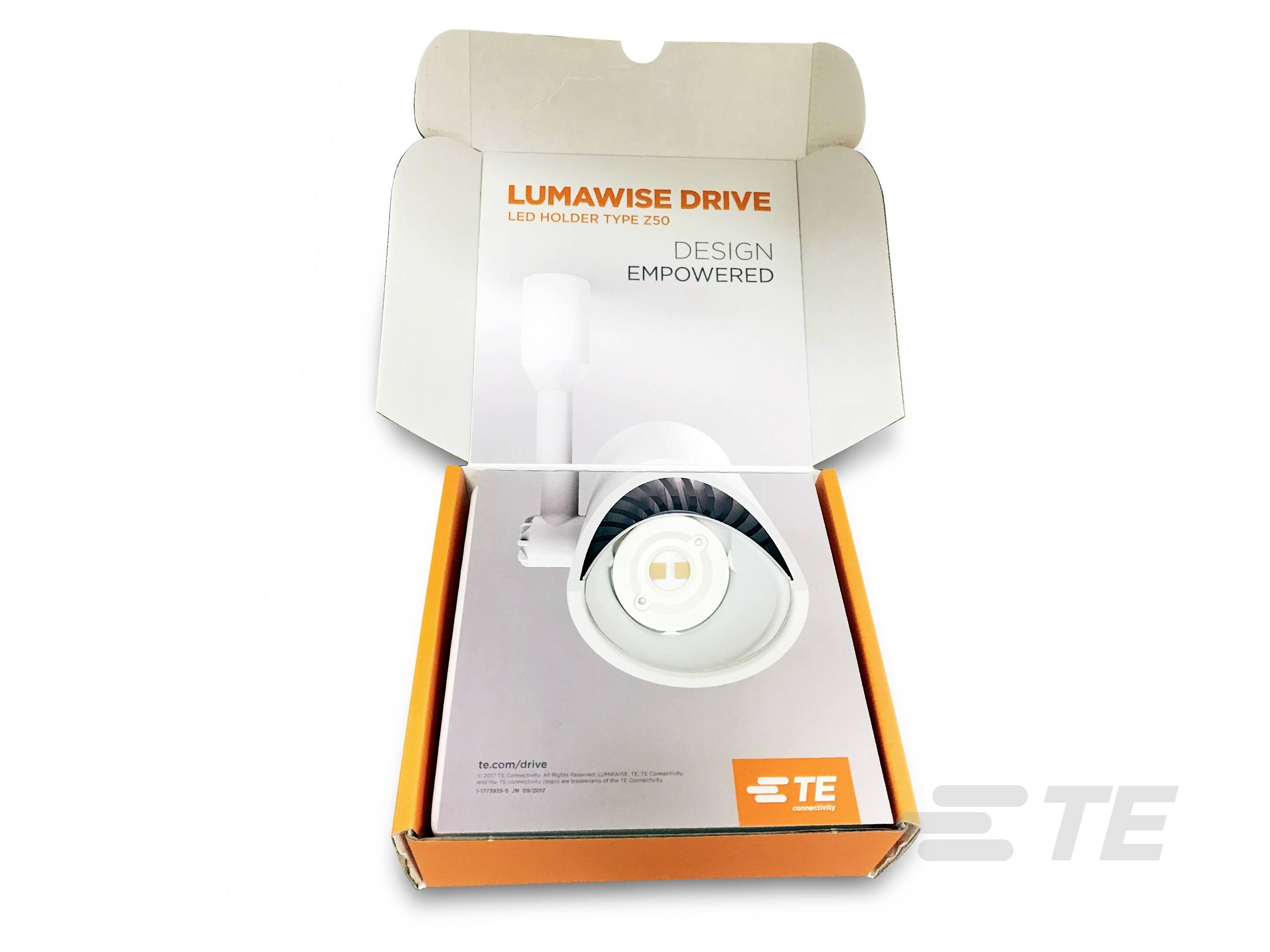 Schachtel mit LED-Halterung 'LUMAWISE DRIVE' von TE. Sichtbare Aufschrift: 'DESIGN EMPOWERED'. Produkt in weißem Karton präsentiert.