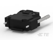 Ein schwarzer, rechteckiger Adapter mit Metallstift und seitlichen Steckverbindungen liegt auf einer weißen Fläche.