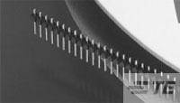 Schwarz-weiß Foto einer Reihe von Stiften aus Metall mit einem geschwungenen Schatten darüber.